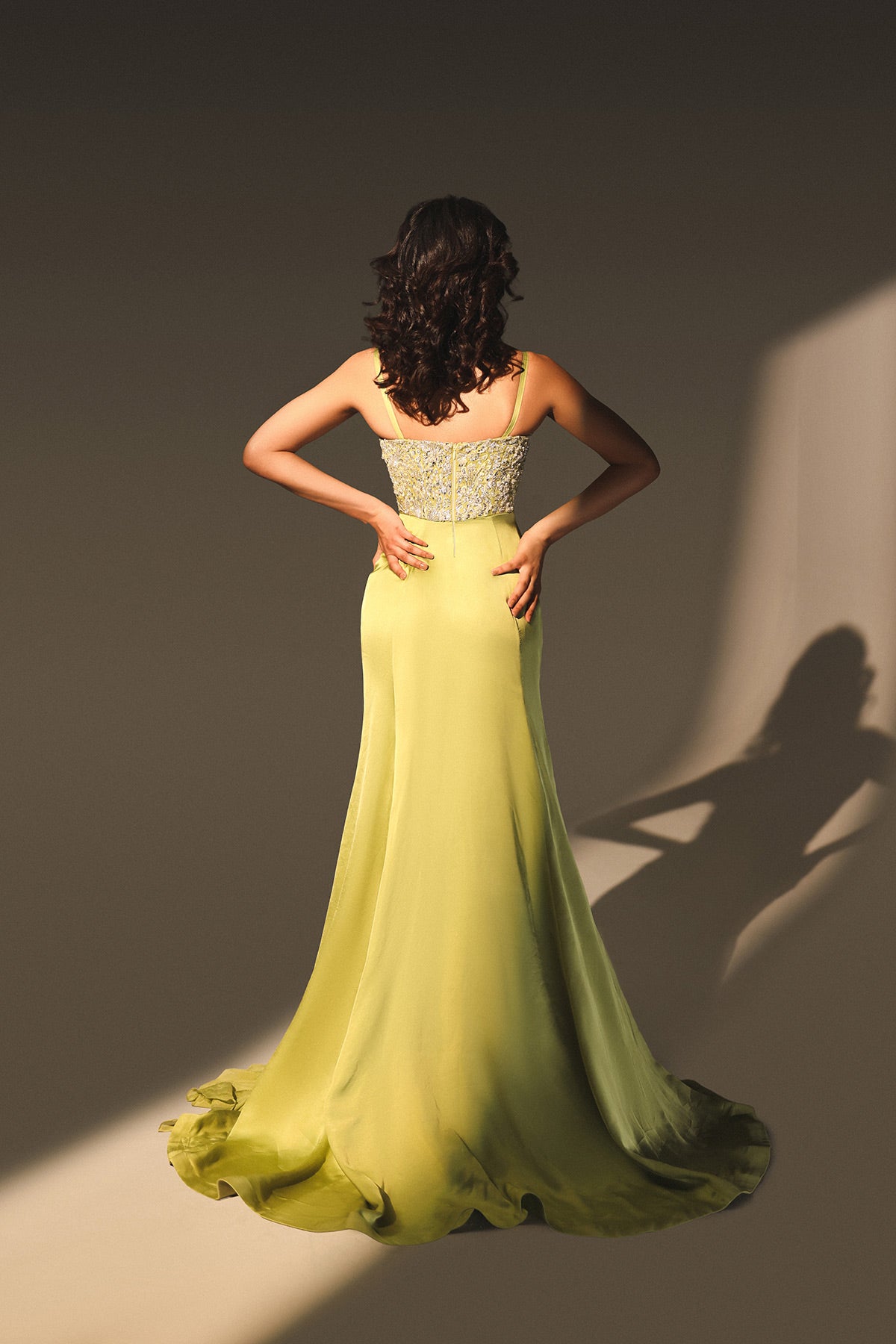 Woman in a yellow evening gown with a silver top against a neutral background