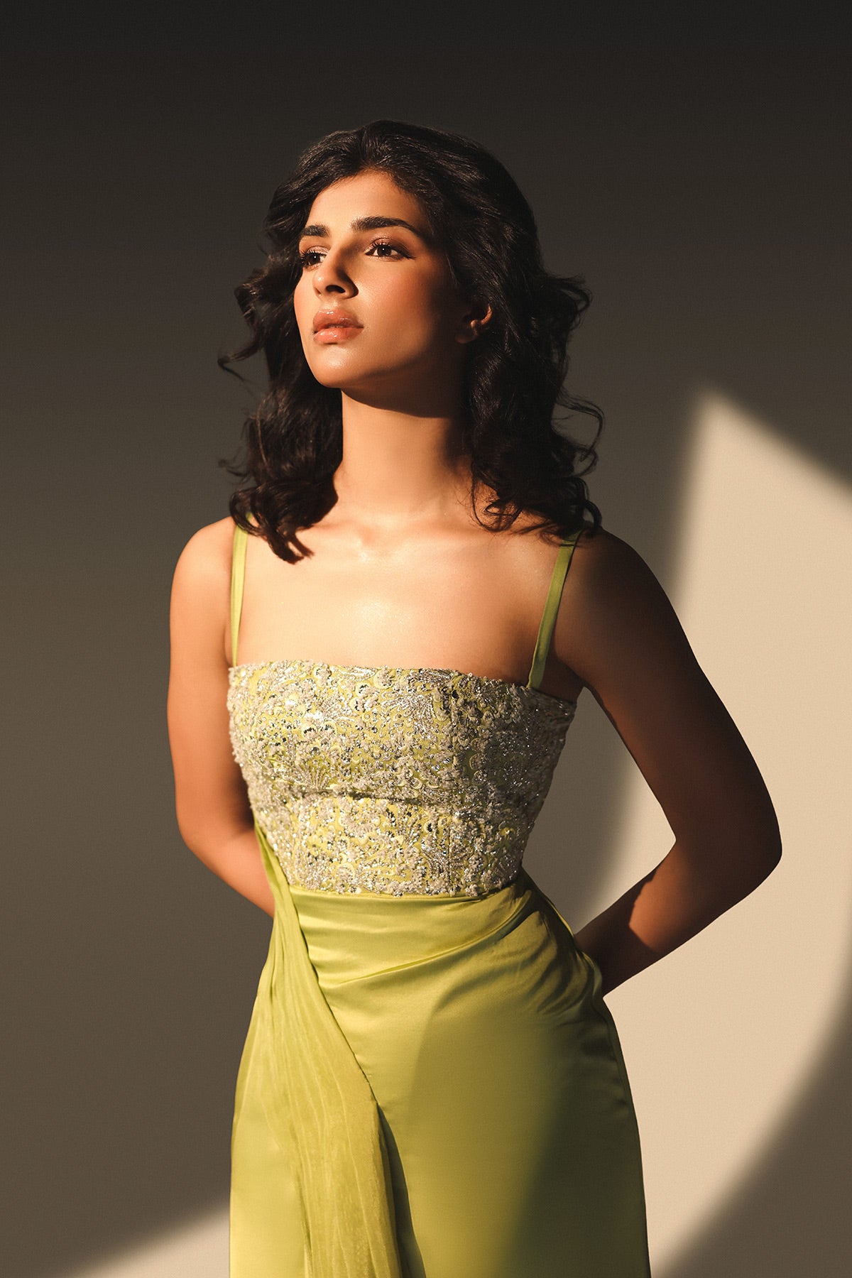 Woman wearing a green dress with floral top against a neutral background