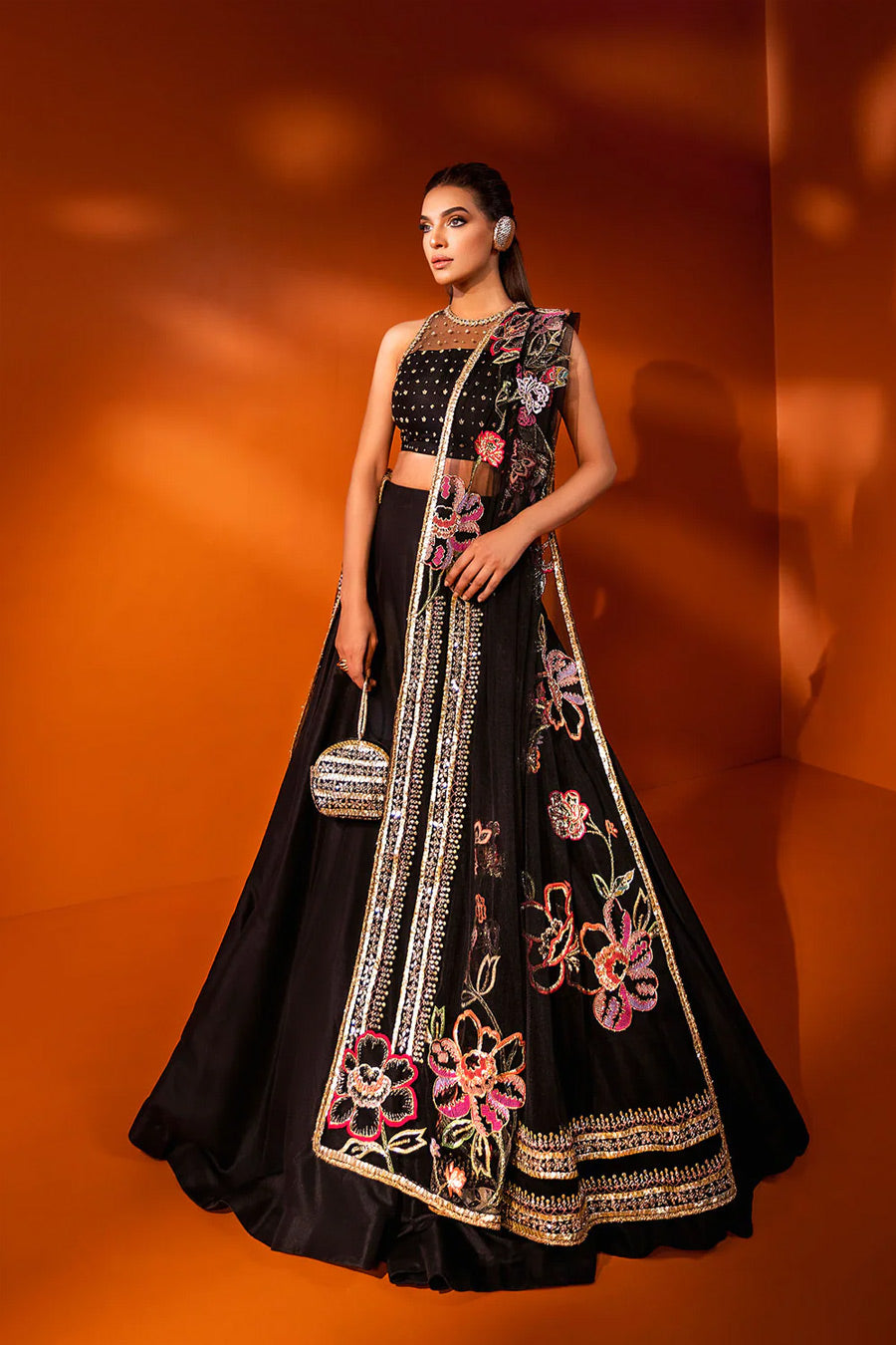 model in a side shot wearing formal black net dupatta paired with net blouse and a silk lehenga