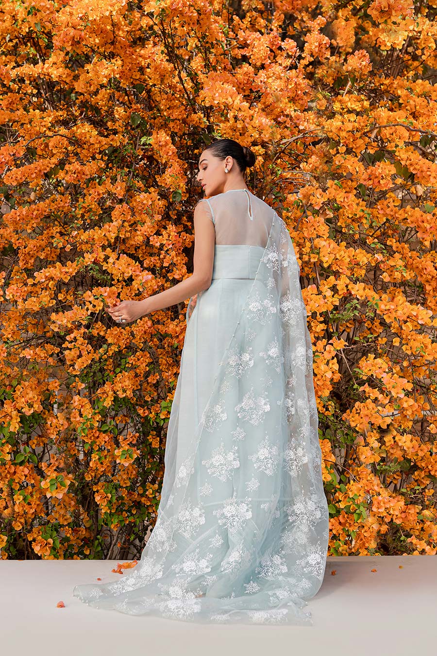 model in a back shot wearing a formal blue organza shirt paired with bamber silk trousers and organza dupatta