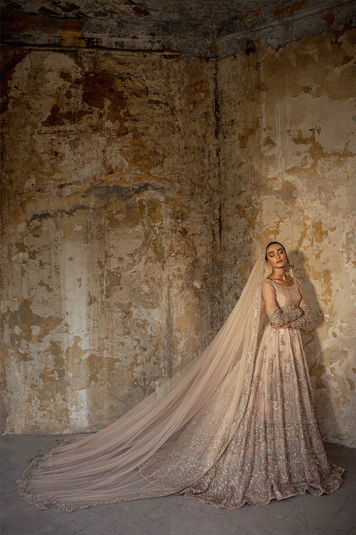 Model in a front shot wearing blush pink silk organza lehenga choli accompanied by a net dupatta and net veil