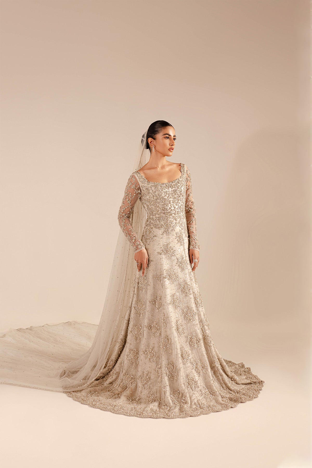 Model in a front shot wearing a net bridal gown with a mermaid fit and train a cathedral-style veil