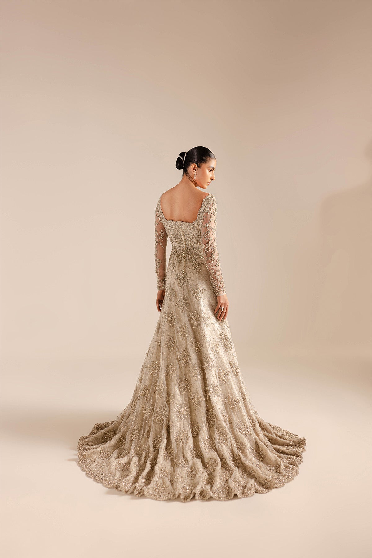 Model in a back shot wearing a net bridal gown with a mermaid fit and train