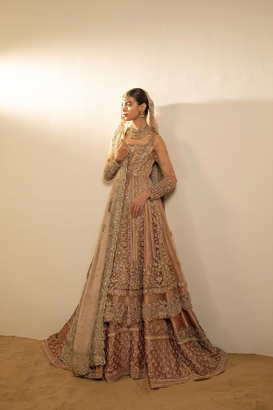 Model in a back shot wearing dusty pink net pishwas combined with a farshi sharara and a dusty pink silk organza dupatta