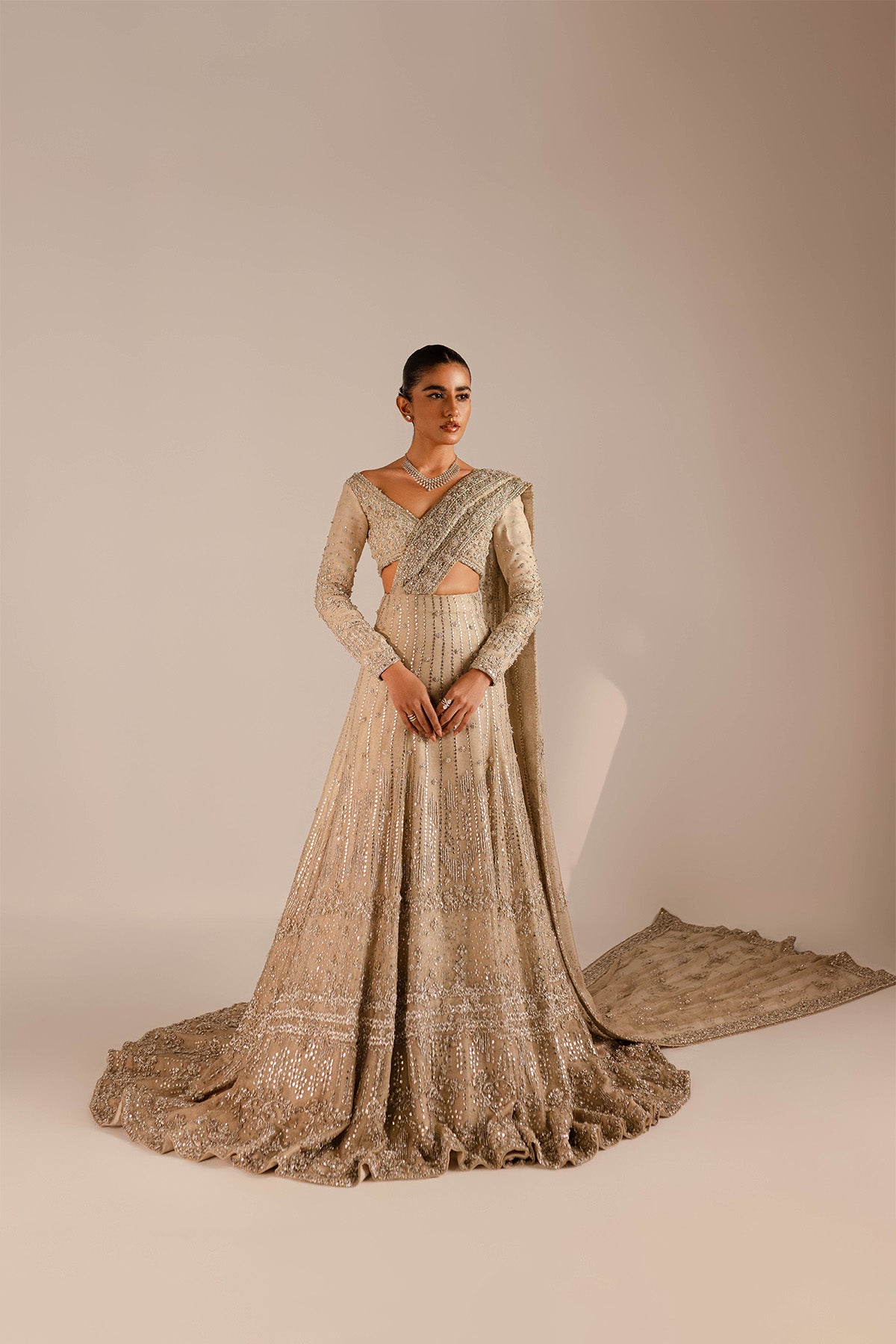 Model in a front shot wearing a gold and silver lehenga with a train and an attached drape