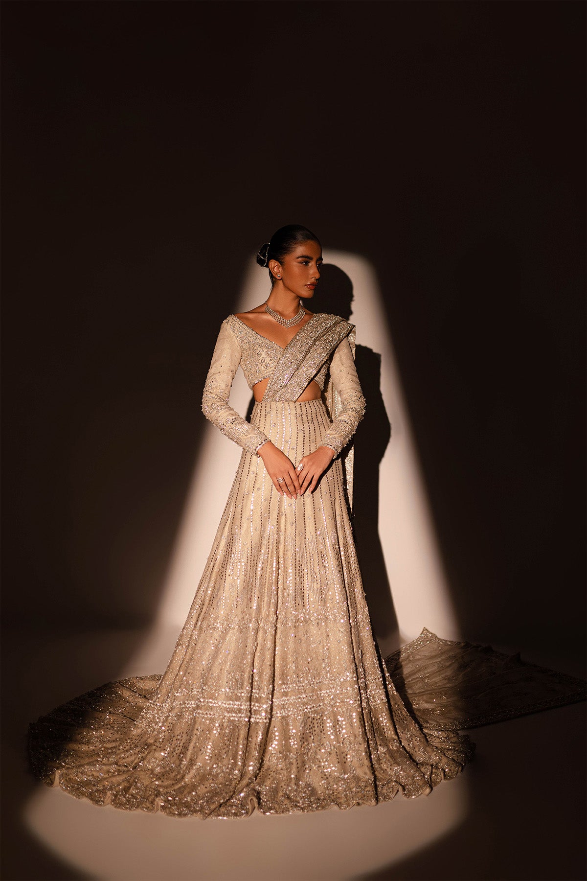 Model in a front shot wearing a gold and silver lehnga with a train