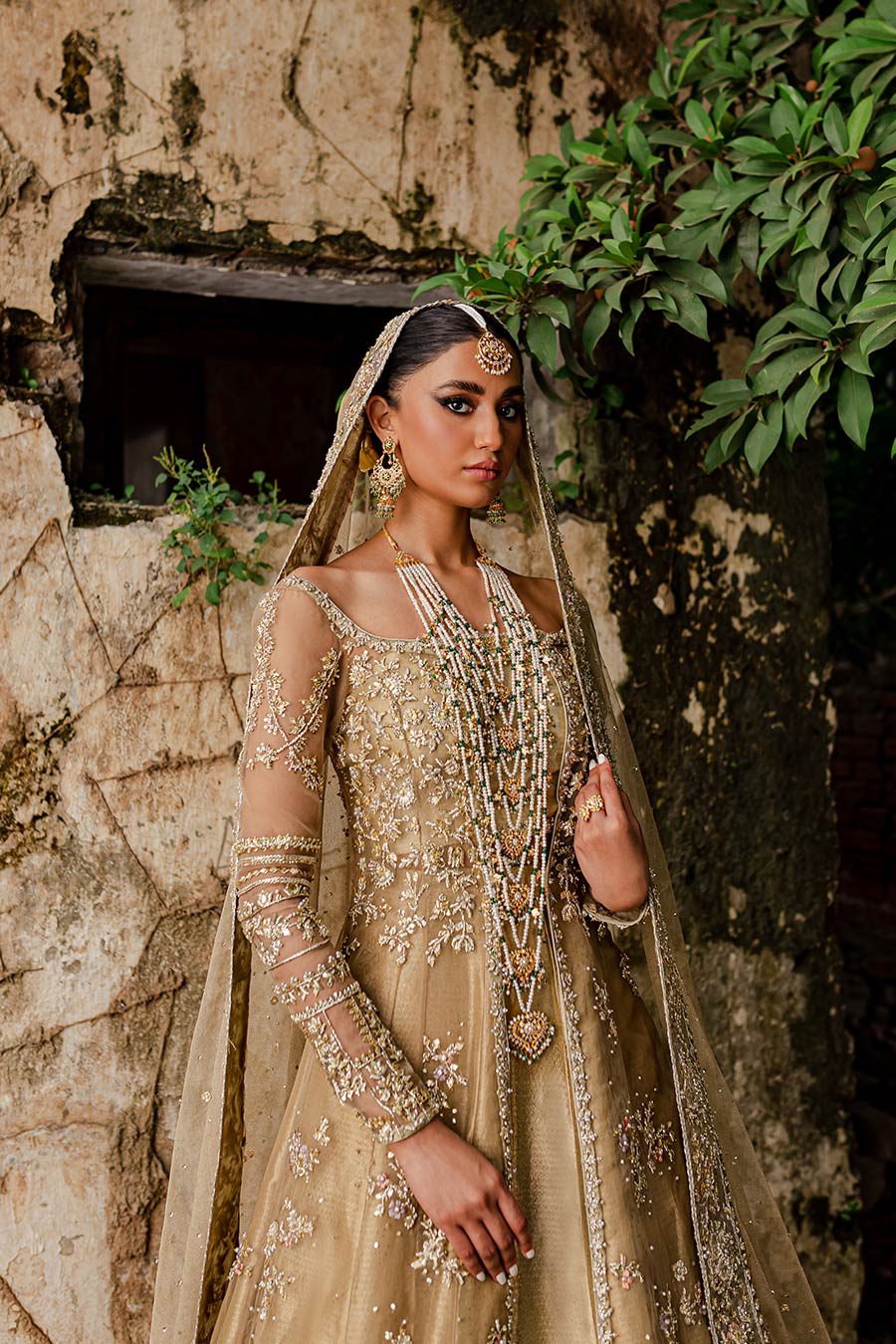 Model wearing a golden front slit organza with zardozi and gota detailing bridal dress by Zuria Dor with front slit shirt