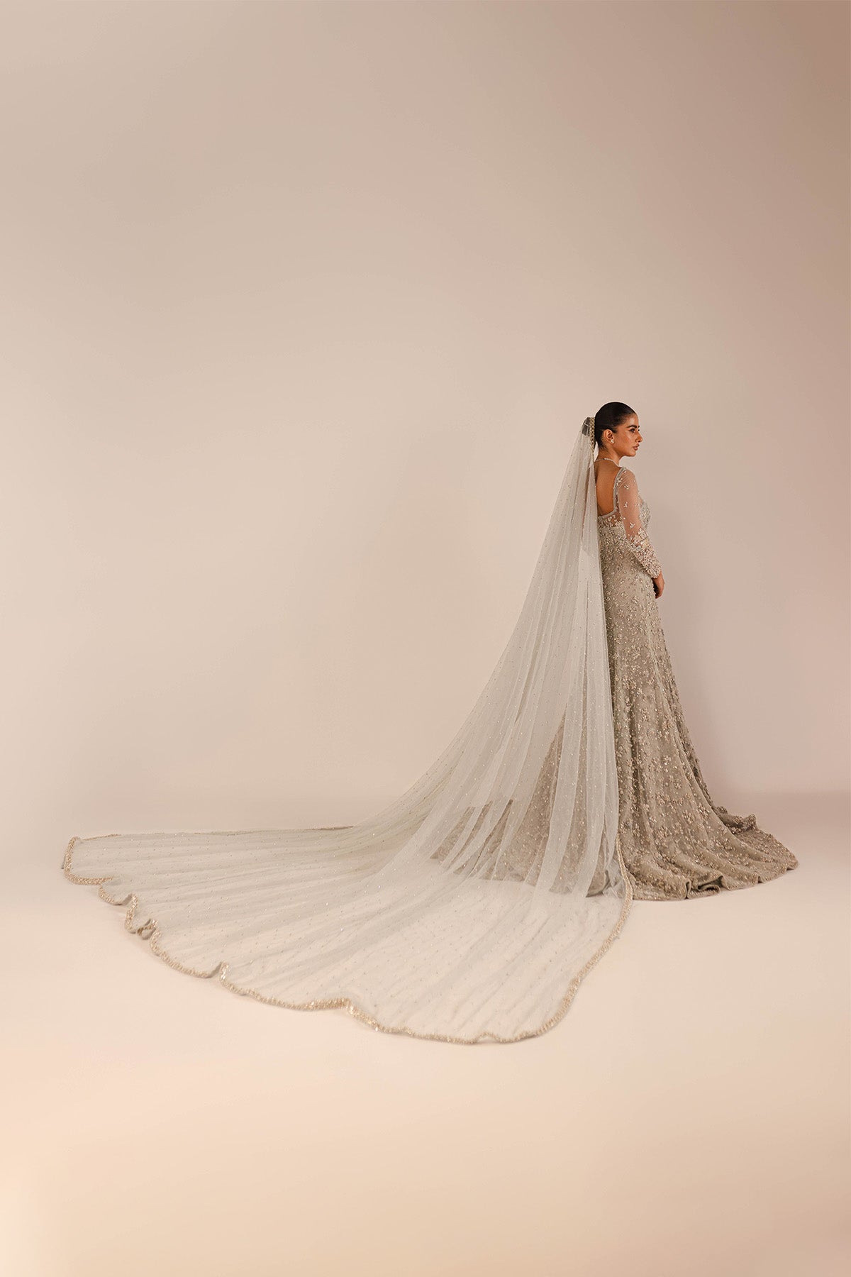 "Model in a side view angle wearing an ice-blue bridal gown along with a veil with a train"