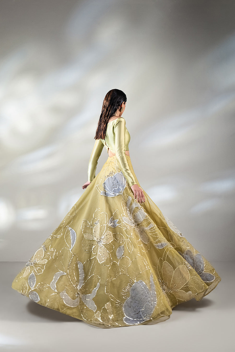 model in a back shot wearing a formal lime green lehenga paired with a solid choli and dupatta