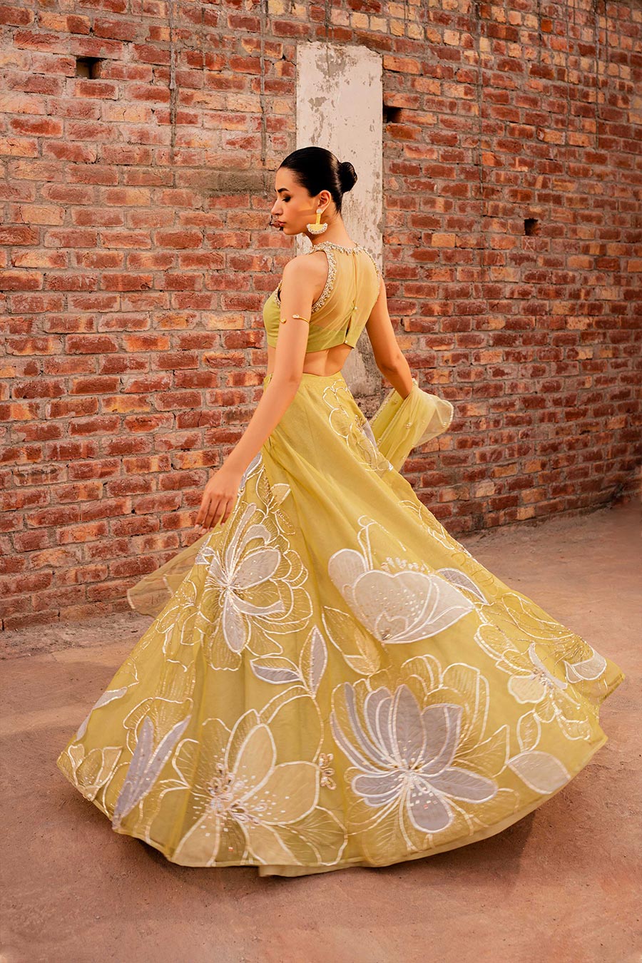 model in a back shot wearing a formal lime green lehenga paired with a blouse and dupatta