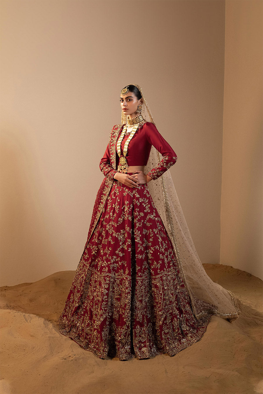 Model in a front shot wearing maroon raw silk lehenga choli paired with silk dupatta and net veil