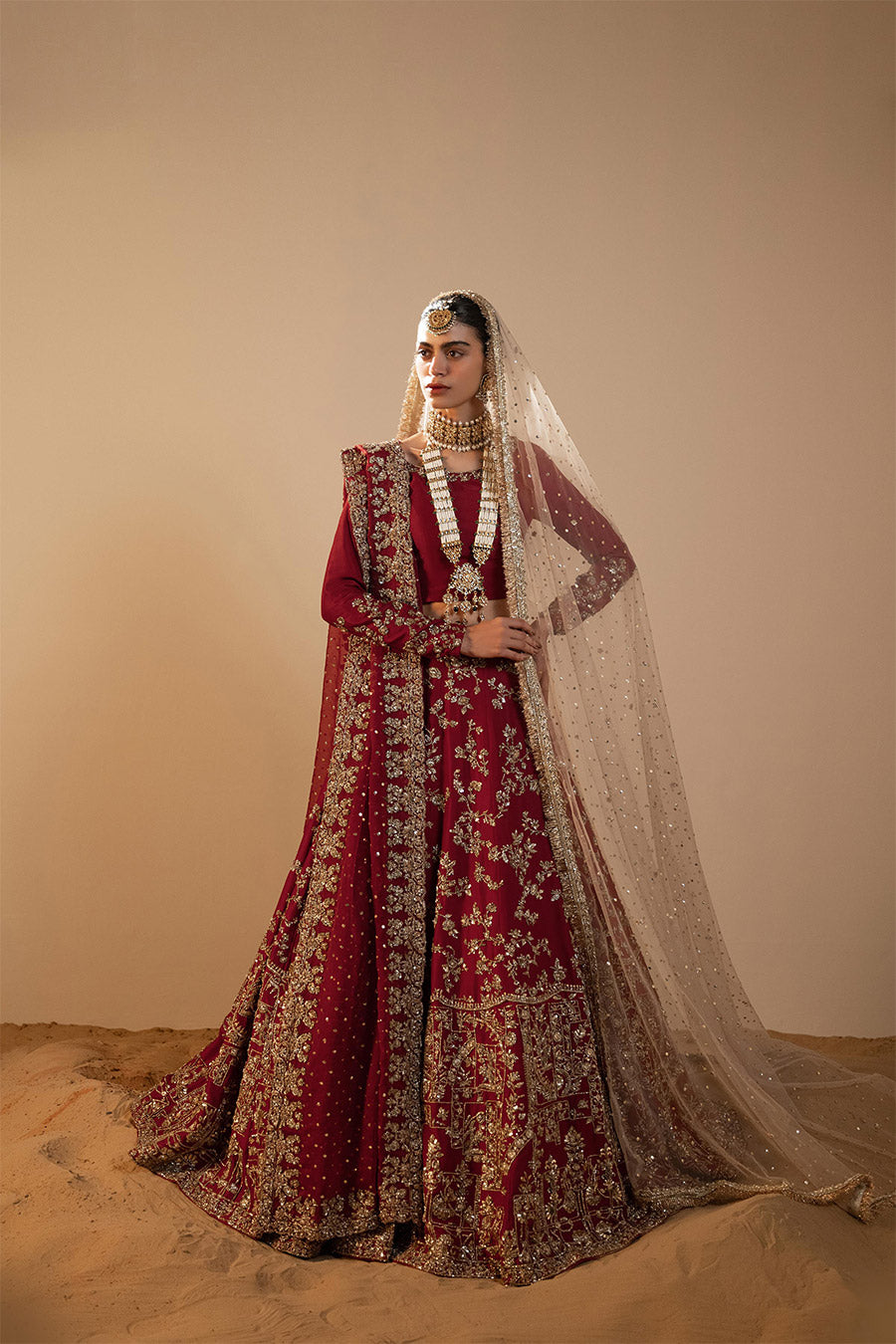 Model in a front shot wearing maroon raw silk lehenga choli paired with silk dupatta and net veil
