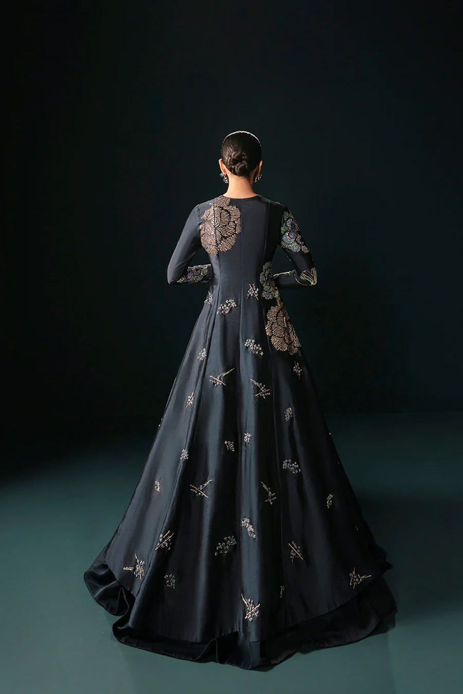 Model in a back shot wearing a midnight blue formal silk jacket paired with a bustier and skirt along with a drape attached to the lehenga