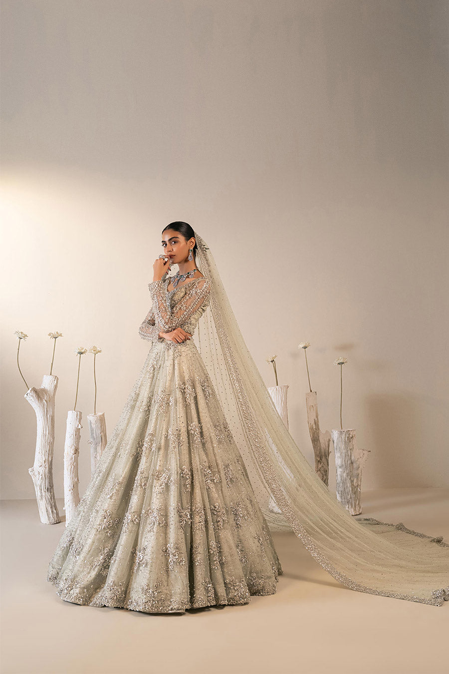 Model in a back shot wearing mint green bridal lehenga choli paired with net veil