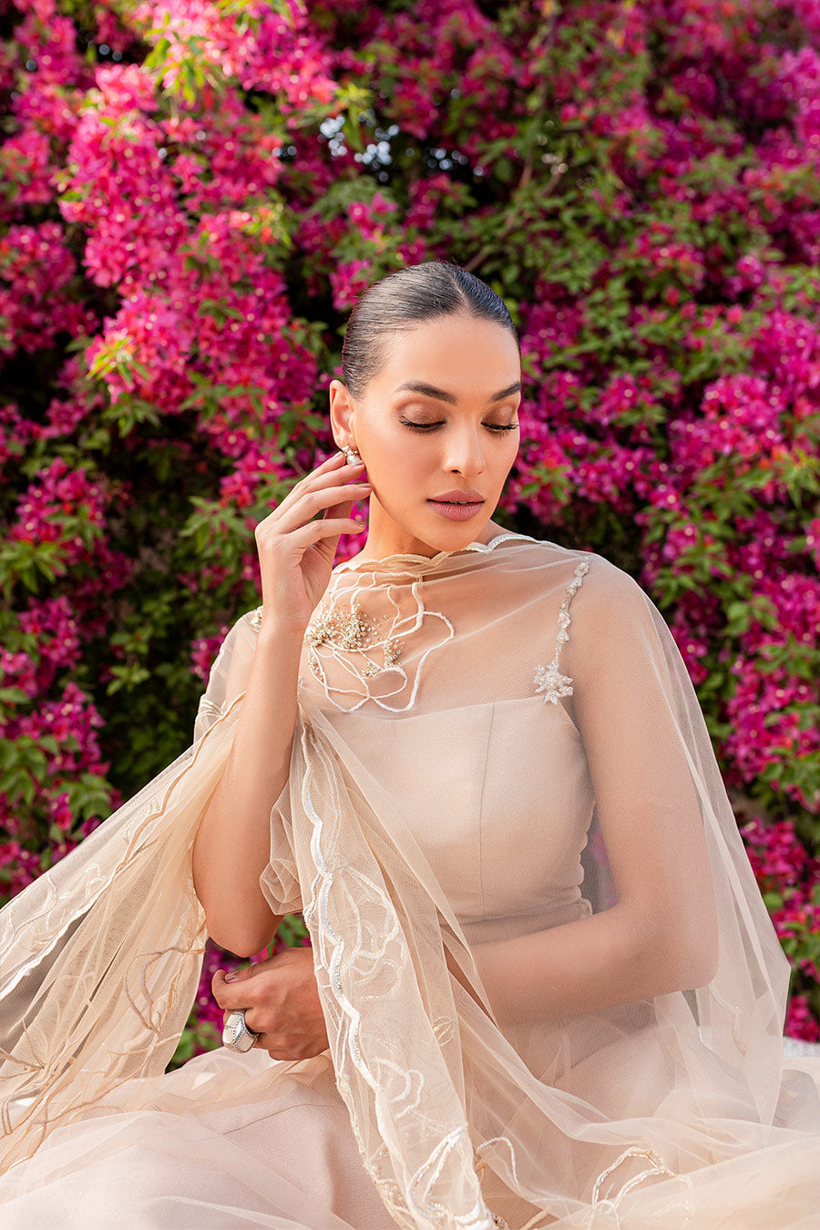 model in a front seated closeup shot wearing a formal nude pink flared net shirt paired with dupatta and a lehenga