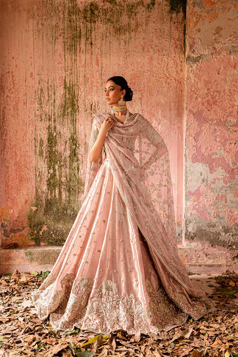Model wearing a plum purple bridal lehenga dress with floral border and motif detailing with thread work, zardozi, sequin, and pearl detailing