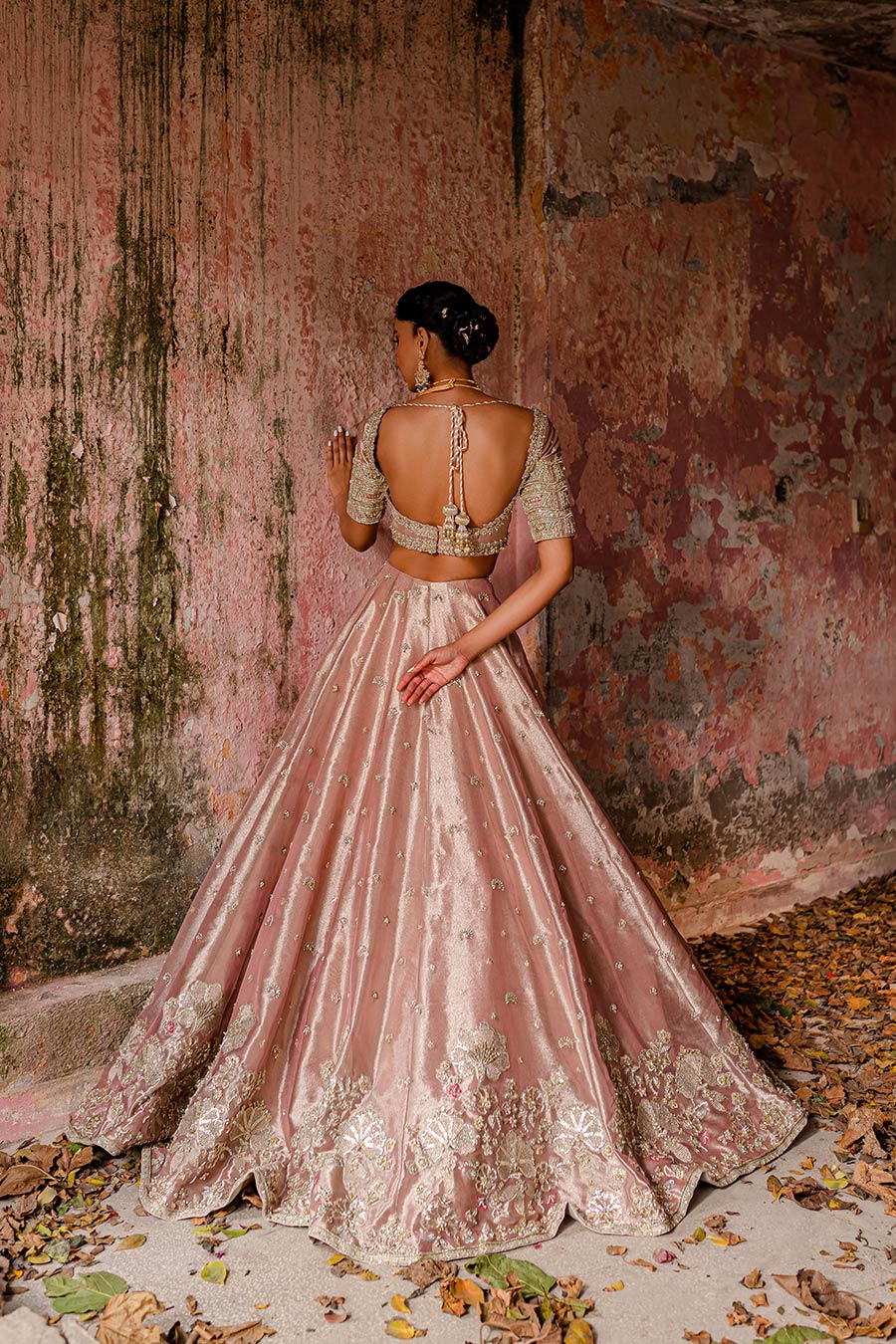 Model wearing a plum purple bridal lehenga dress with floral border and motif detailing with thread work, zardozi, sequin, and pearl detailing