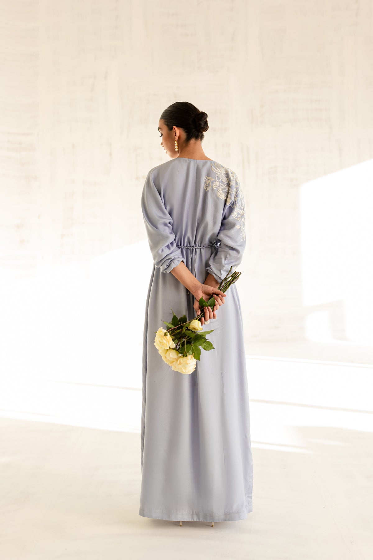 Model in a back view shot wearing a sky blue embroidered kaftan