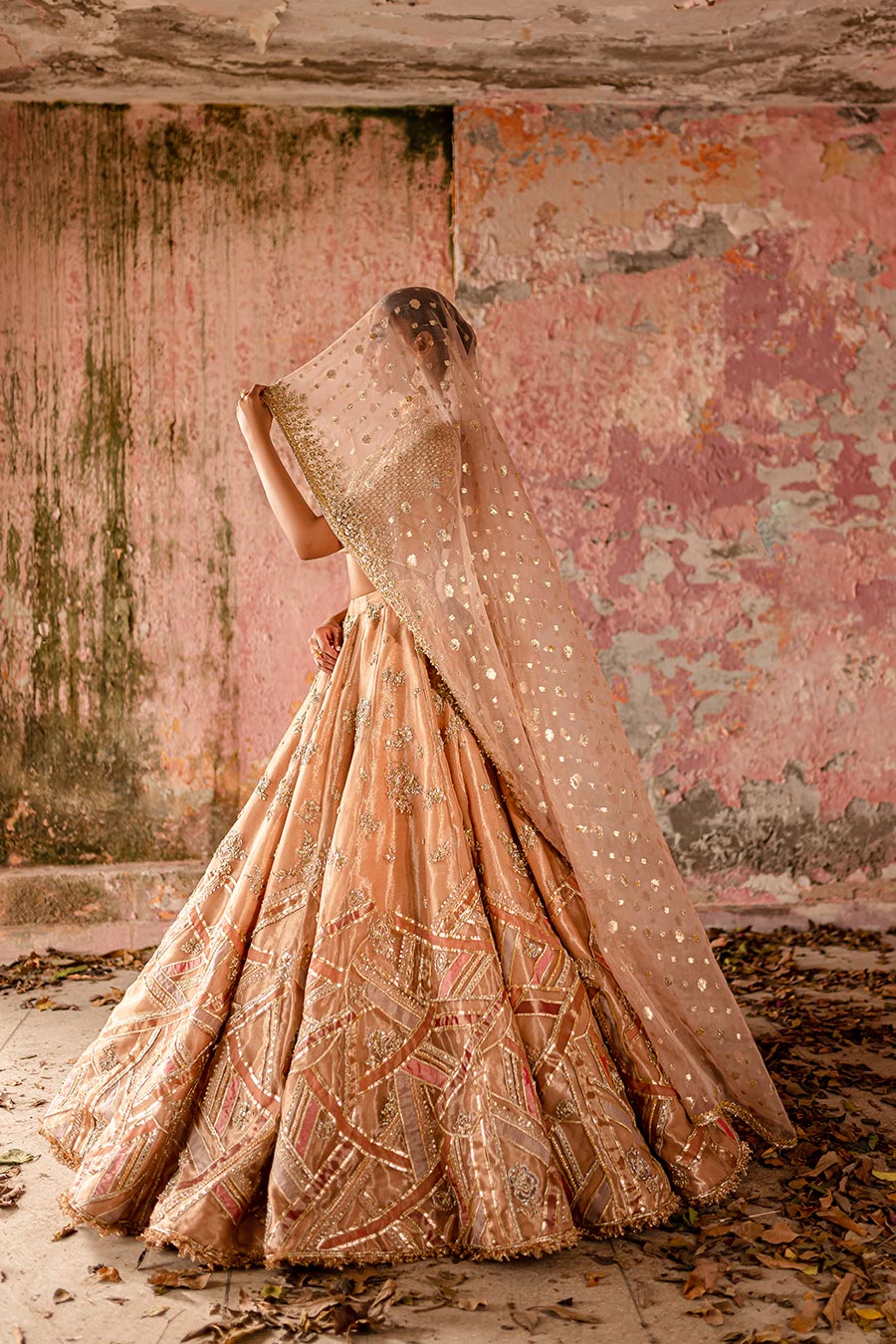Model wearing a warm peach bridal lehenga dress with thread work, zardozi, and sequin embellishments with pastle pink dupatta by Zuria Dor