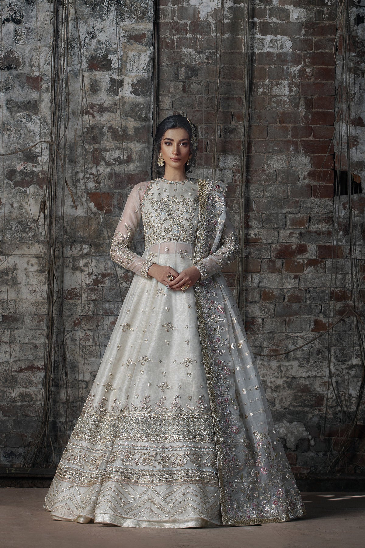 Model in a front view shot wearing long pishwas gown in organza silk paired with an organza zari dupatta and organza lehenga
