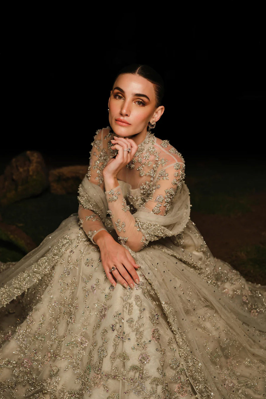 Model in a top closeup shot wearing a white bridal pishwas with organza lehenga and long flowing drapes attached to the back
