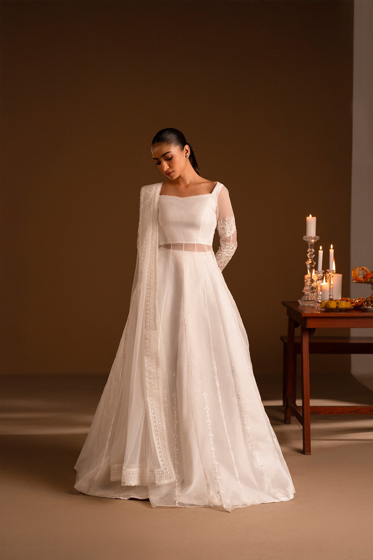 Model in a front shot wearing a long flared pishwas with embroidered shirt and organza dupatta.