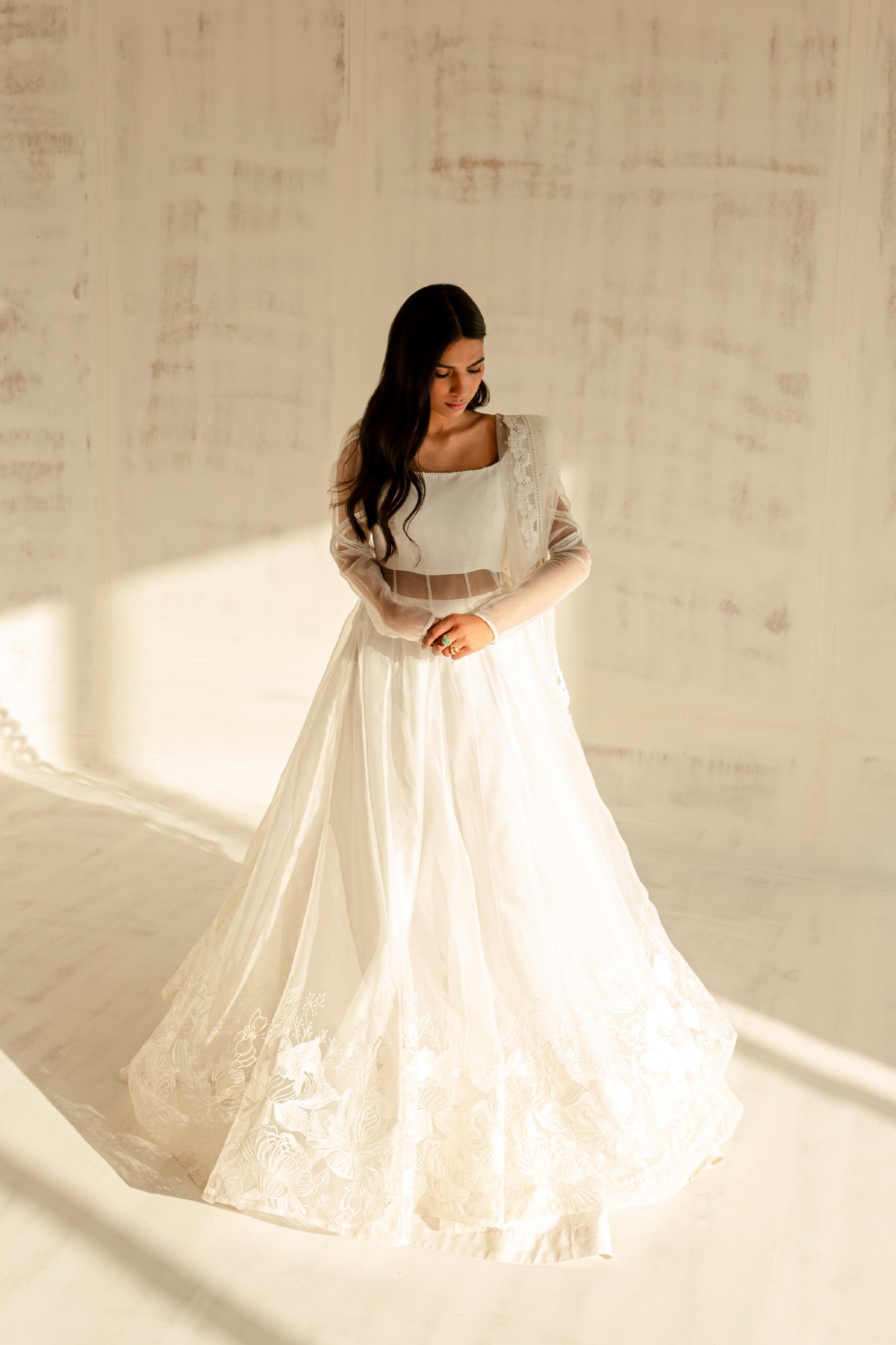Model in a front view shot wearing a white organza shirt paired with an organza dupatta and a silk katan lehenga