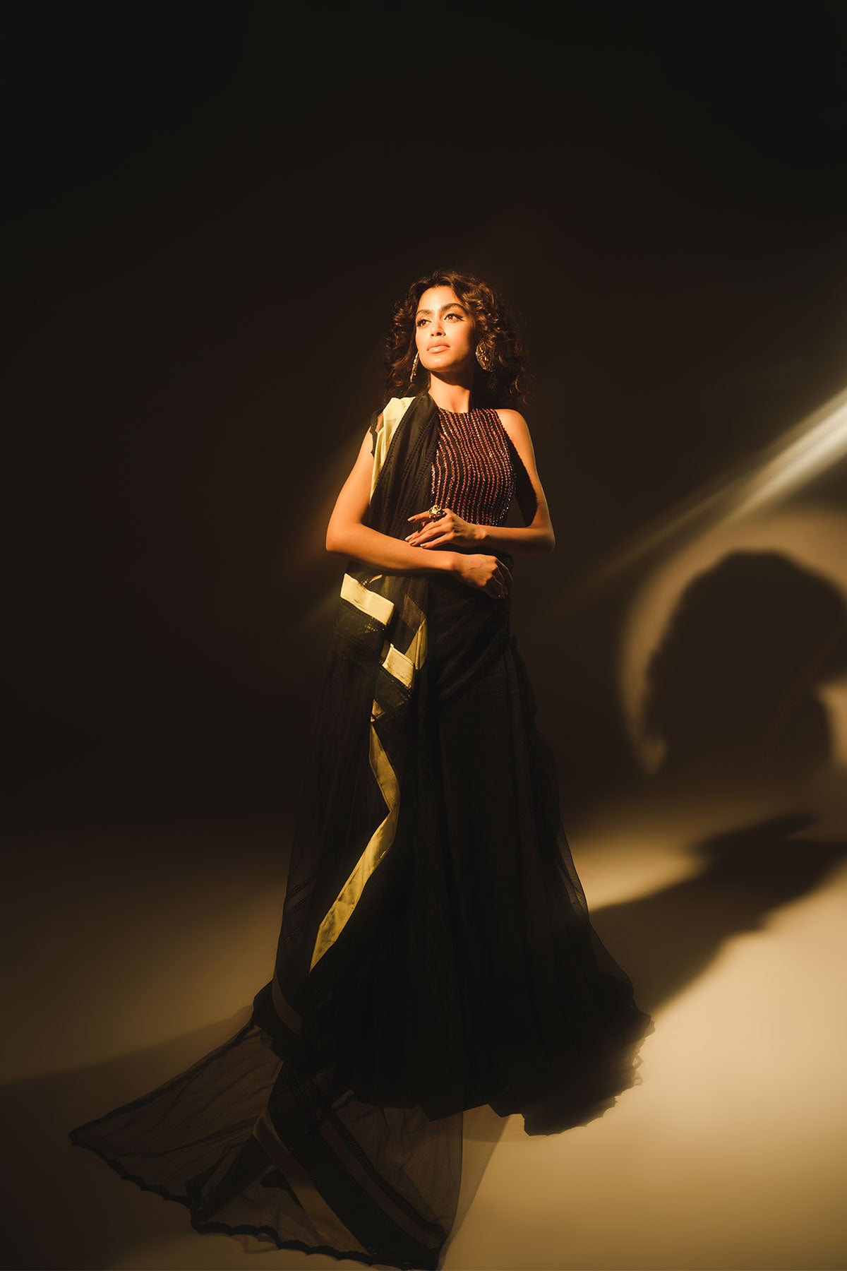 Model in a front shot wearing black formal lehenga saree paired with lehenga and a net saree drape
