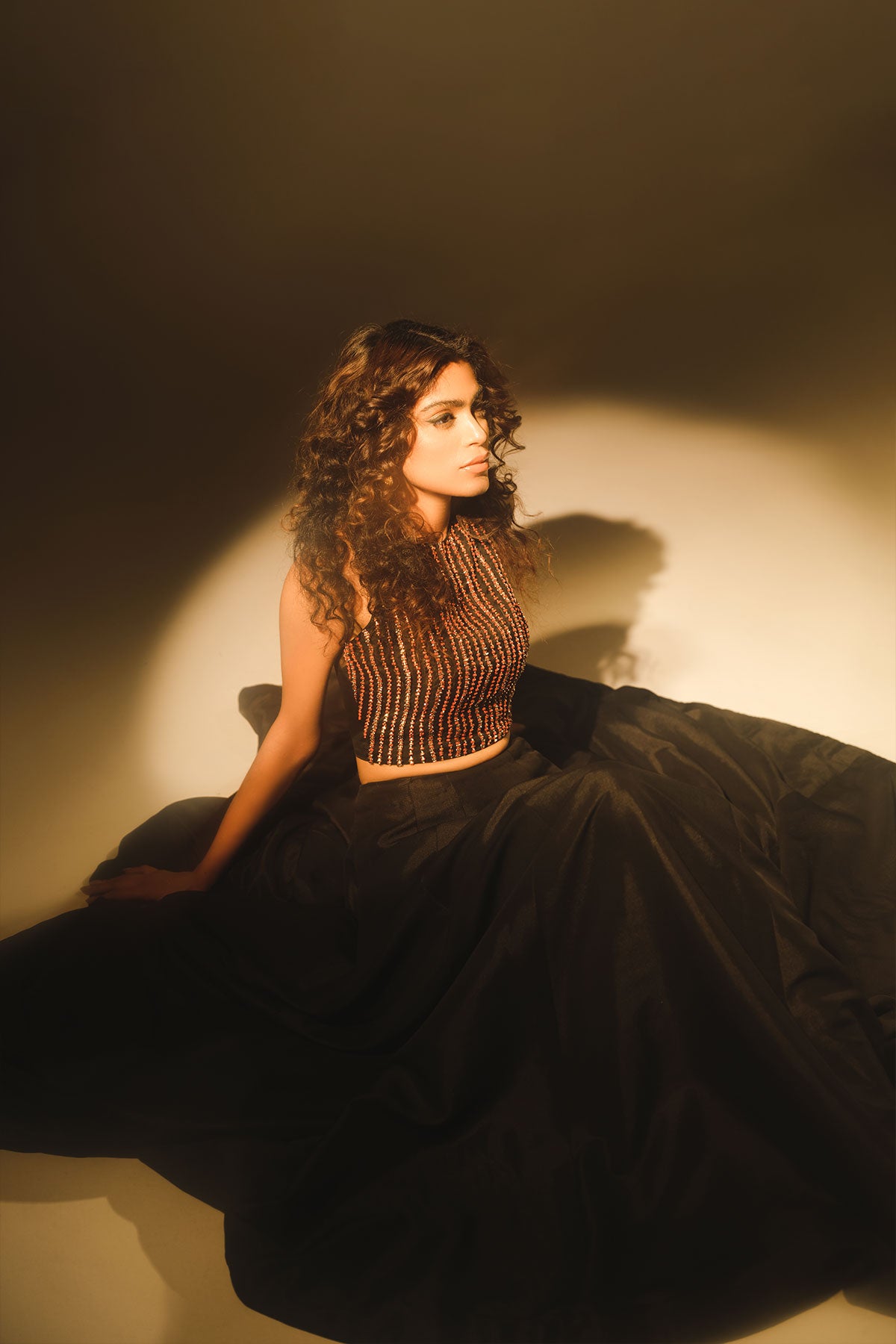 Model in a side shot wearing black formal lehenga saree paired with lehenga and a net saree drape