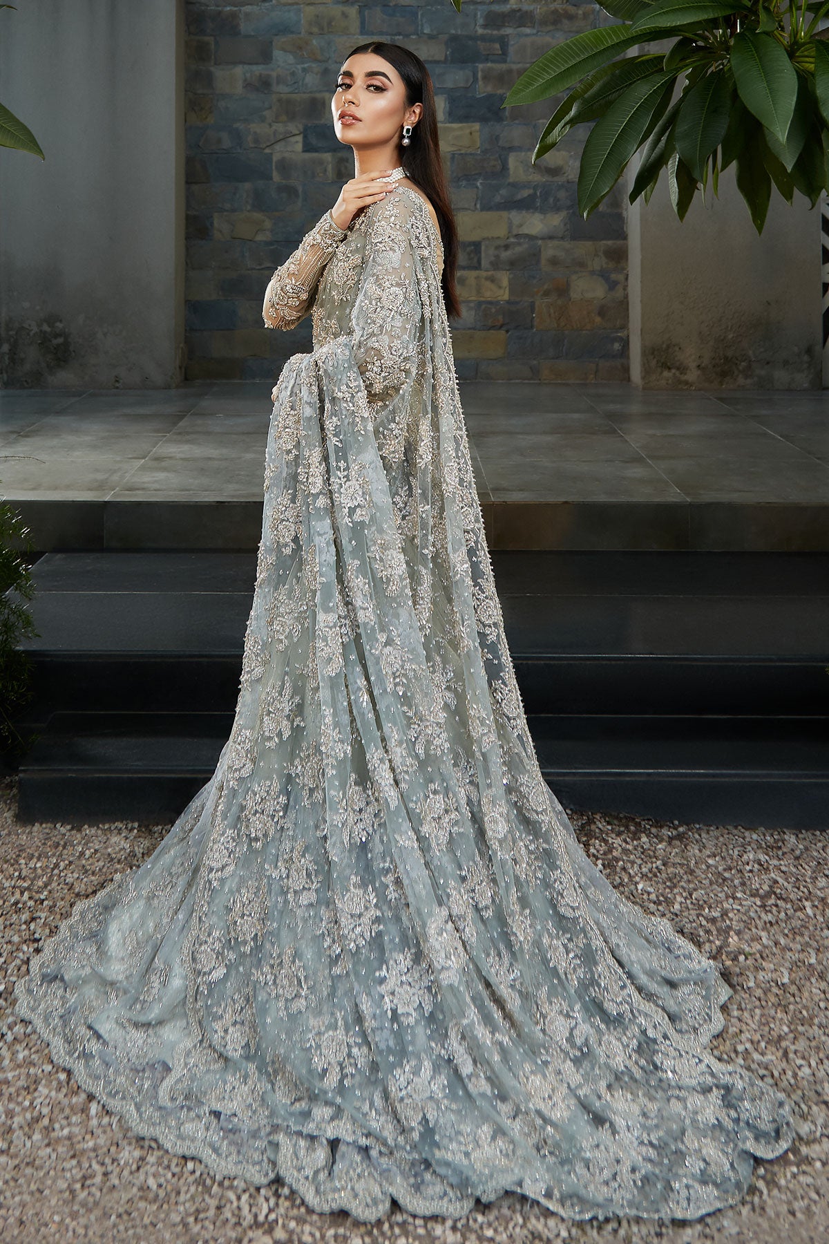 model in a side shot wearing blue bridal saree with net blouse and silk brocade lehenga