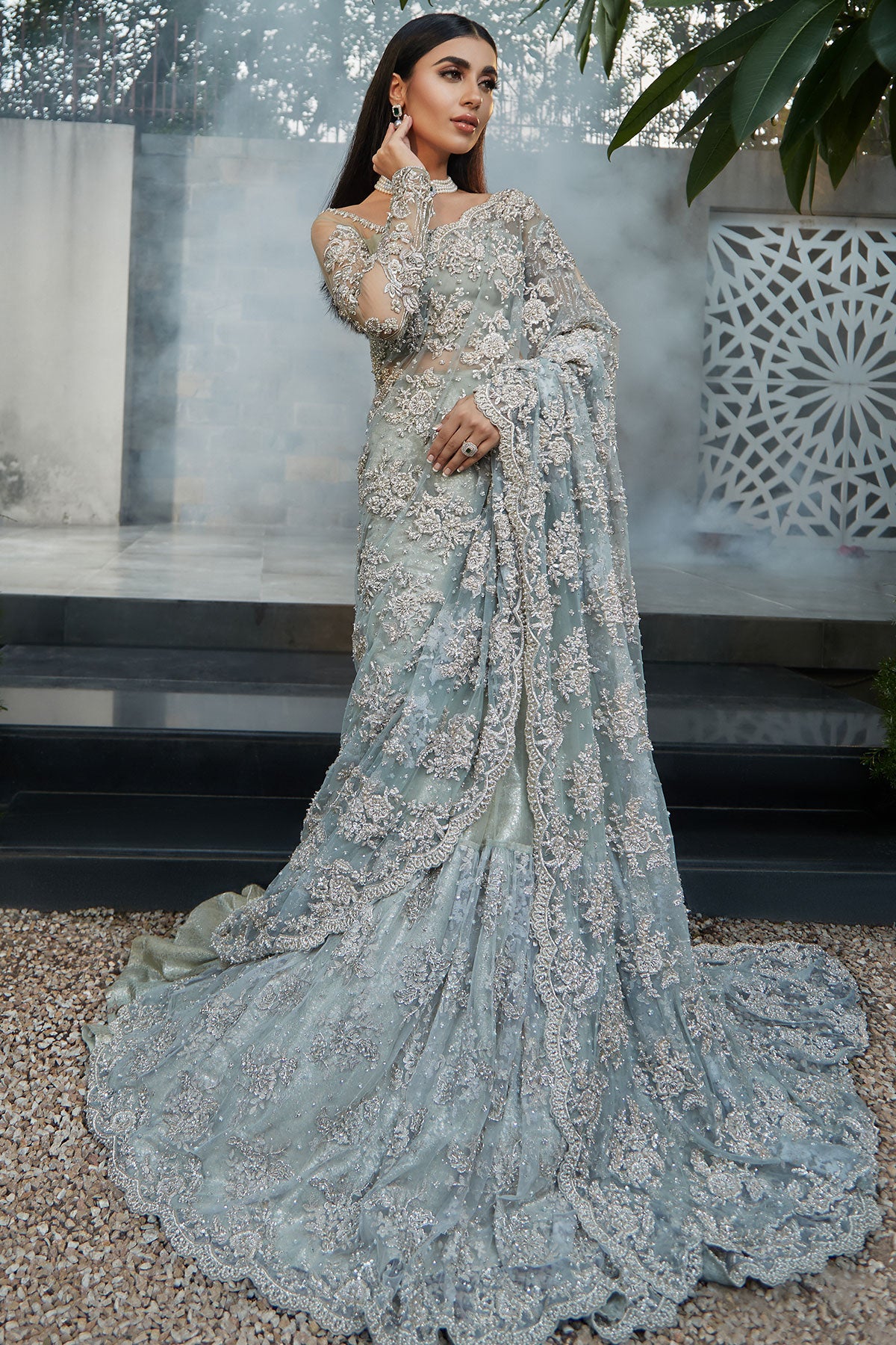model in a front shot wearing blue bridal saree with net blouse and silk brocade lehenga