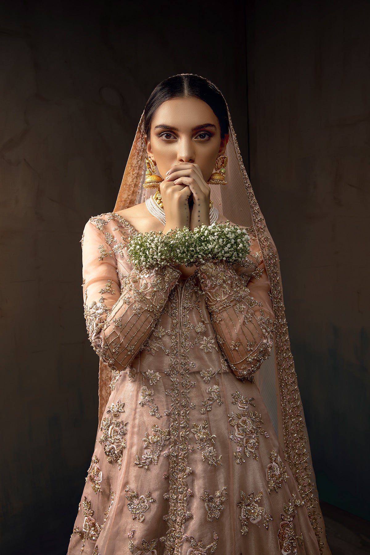 Model in a front closeup shot wearing blush pink bridal gown with a front slit paired with pink masuri organza dupatta