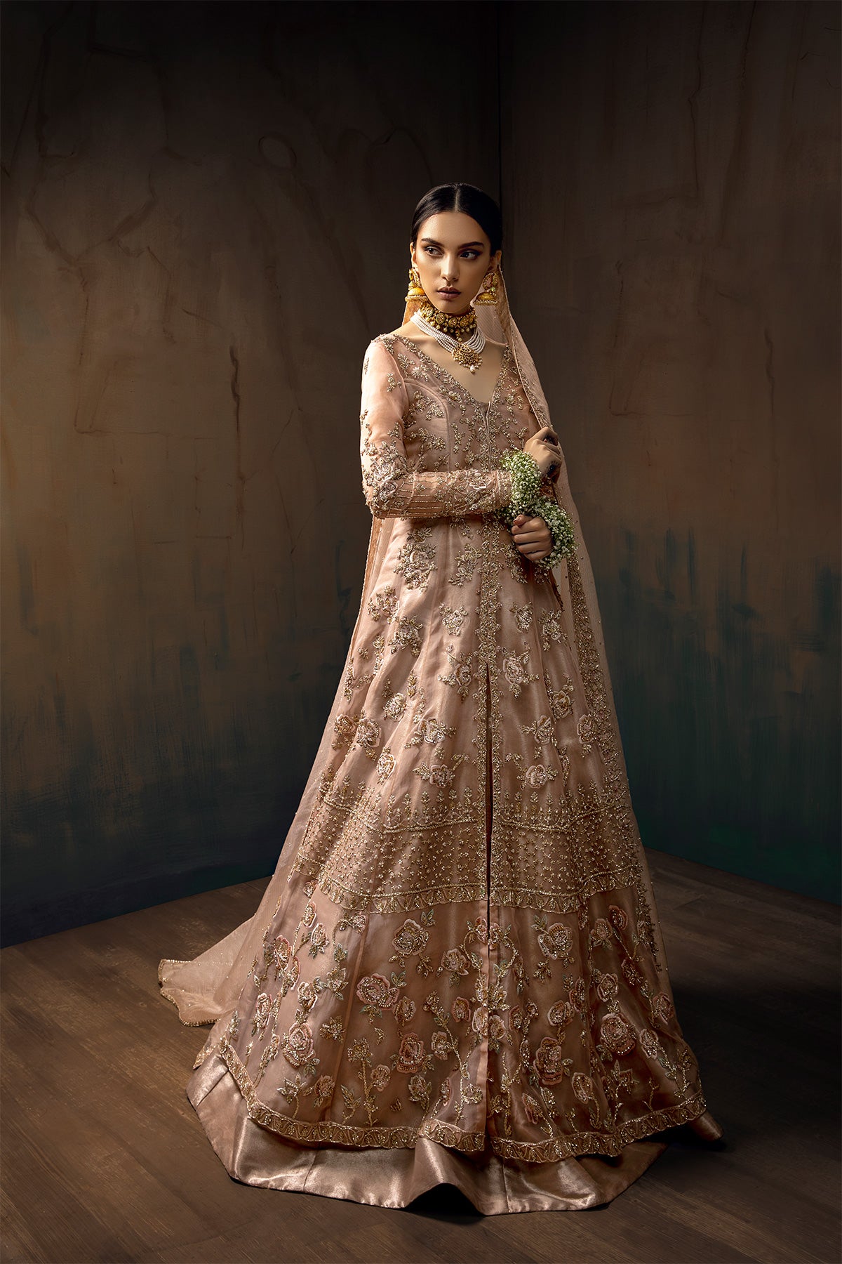 Model in a front full shot wearing blush pink bridal gown with a front slit paired with rose gold tissue lehenga and pink masuri organza dupatta