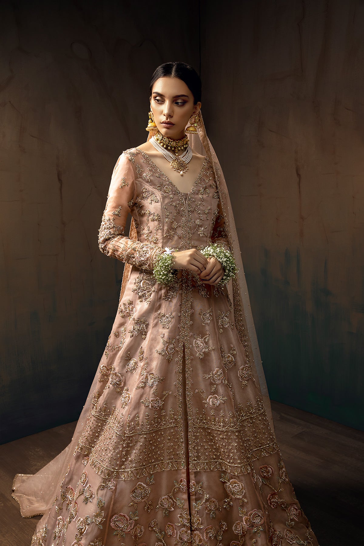 Model in a front full shot wearing blush pink bridal gown with a front slit paired with rose gold tissue lehenga and pink masuri organza dupatta