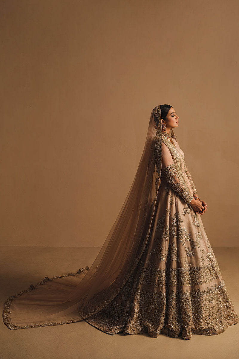 Rabia Butt in a side shot wearing blush pink silk organza lehenga choli accompanied by a net dupatta and net veil