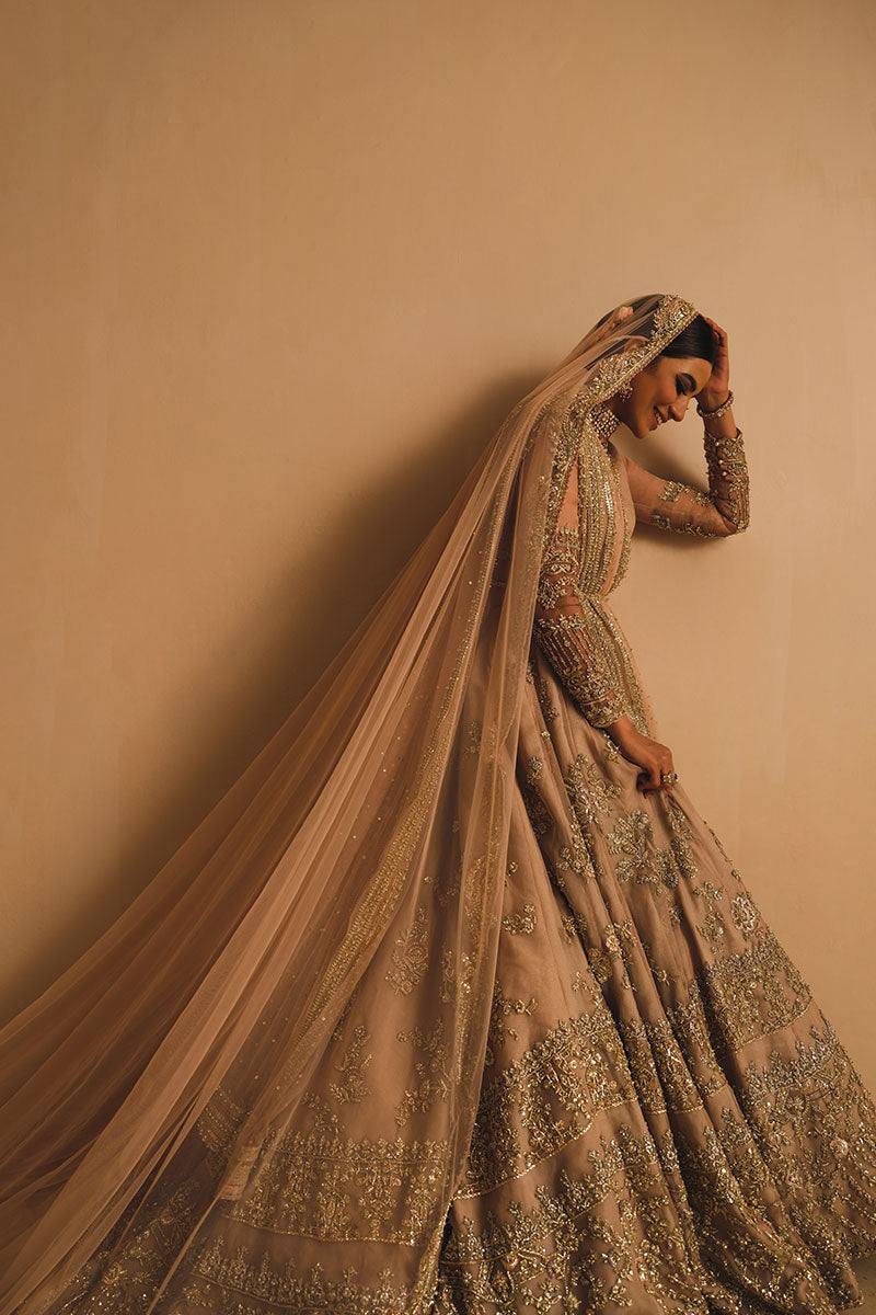 Rabia Butt in a side shot wearing blush pink silk organza lehenga choli accompanied by a net dupatta and net veil
