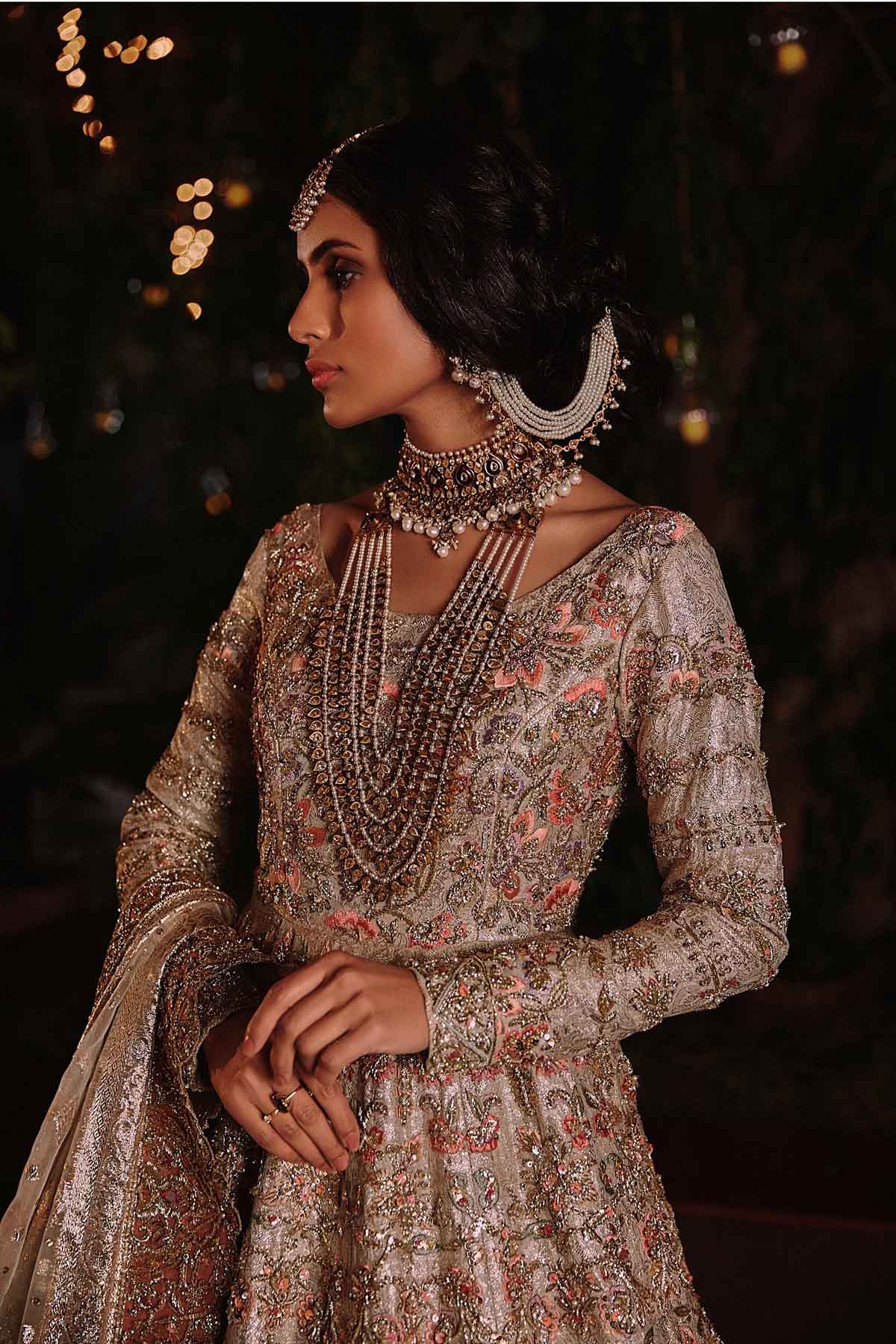 model in a closeup side shot wearing ivory bridal silk brocade pishwas, with a lilac lehenga and an ivory dupatta