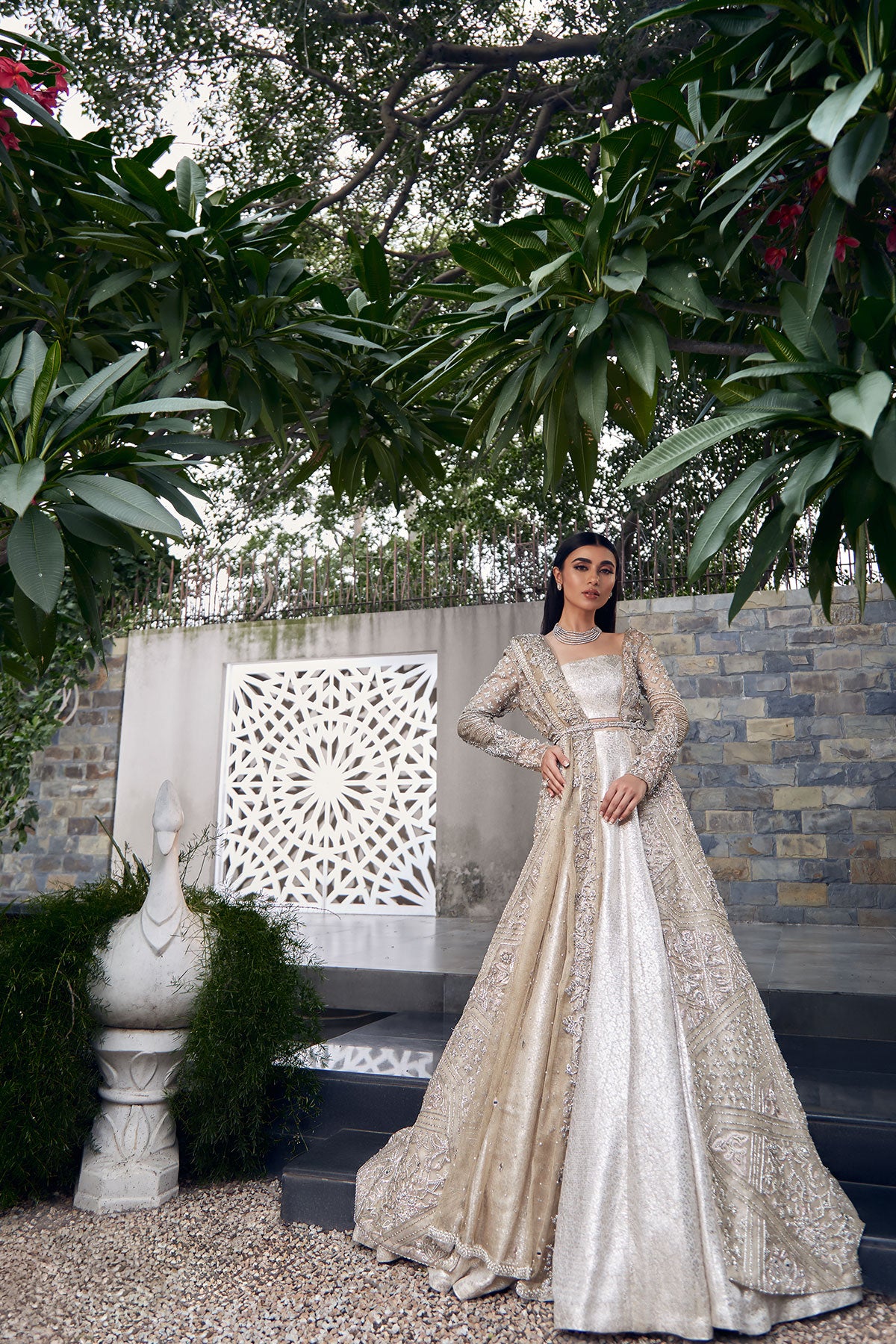 model in a side shot wearing bridal kundan net front-open long gown paired with a brocade bustier and lehenga and dupatta