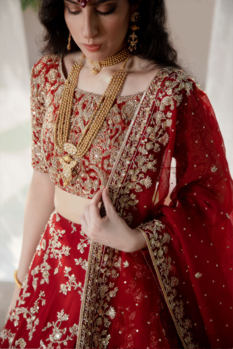 Model in a closeup shot wearing maroon raw silk bridal lehnega paired with organza dupatta and silk brocade choli