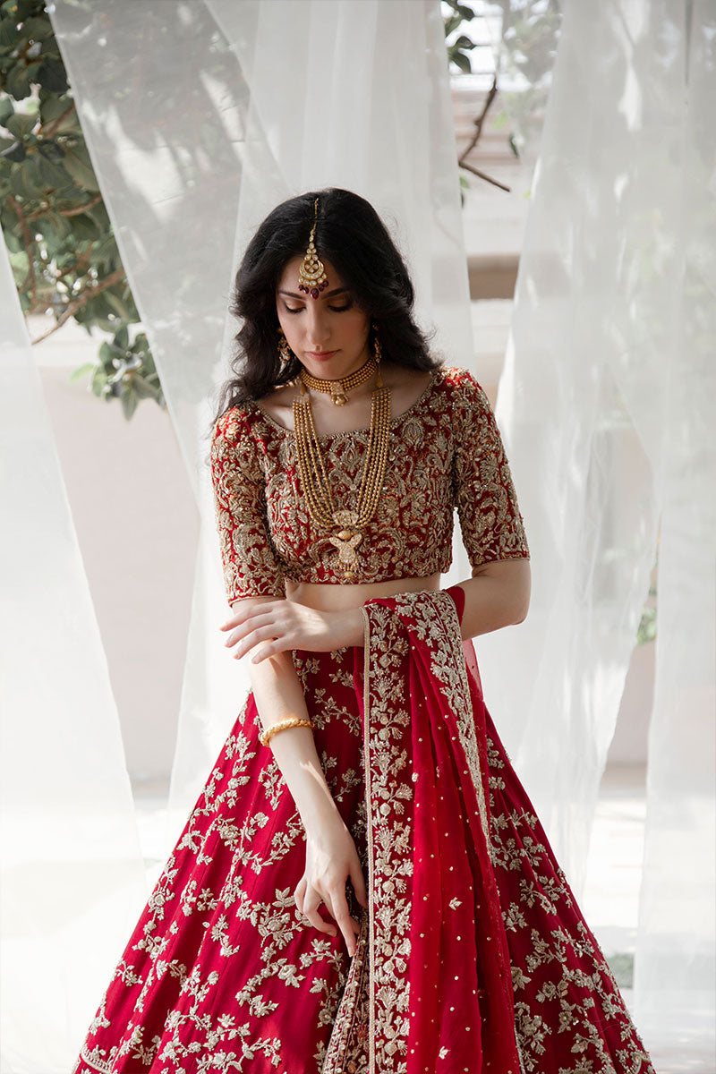 Model in a low front shot wearing maroon raw silk bridal lehnega paired with organza dupatta and silk brocade choli