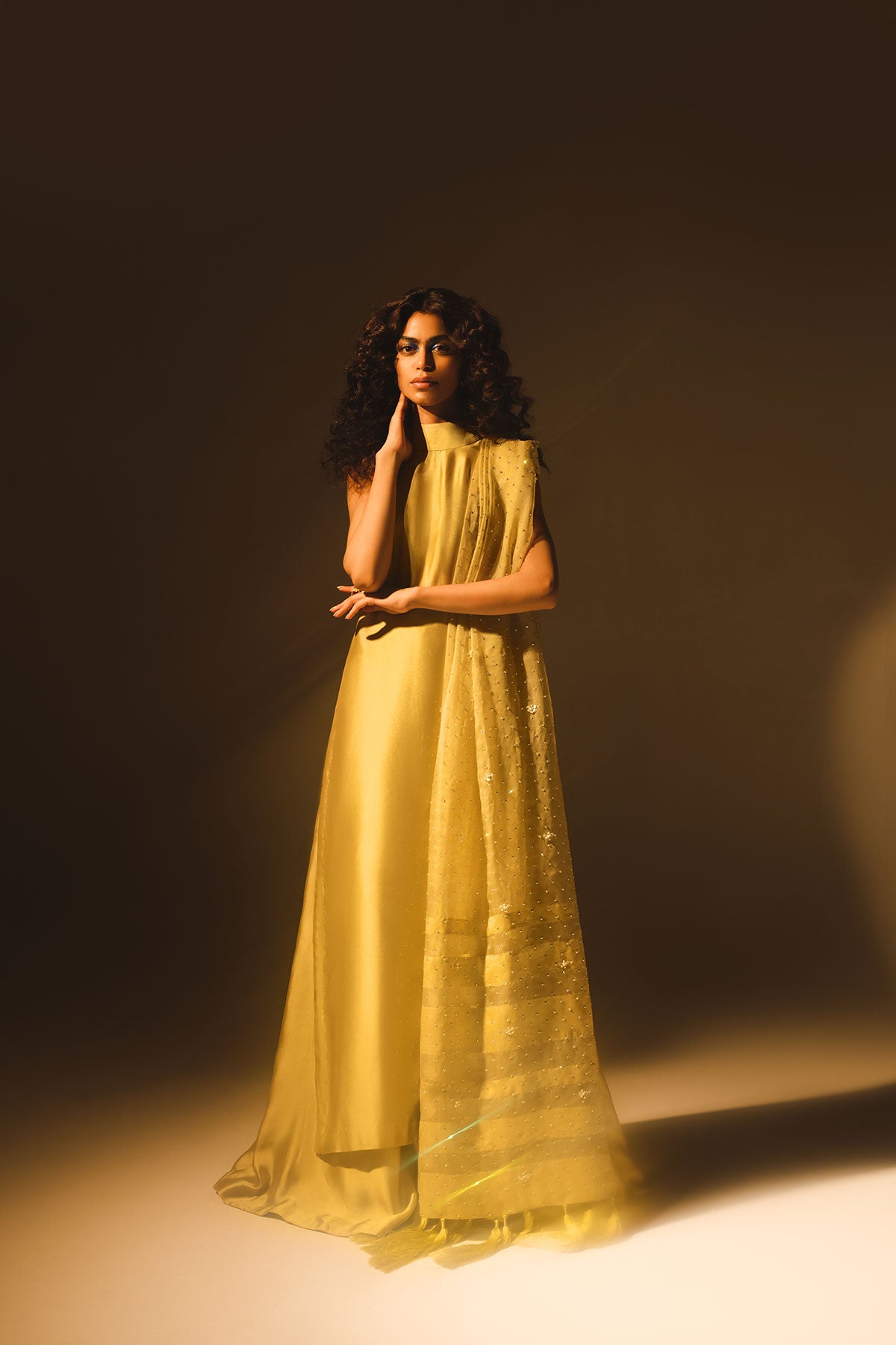 Model in a front shot wearing mustard tissue silk shirt with a halter neckline paired with flared pants and silk organza dupatta