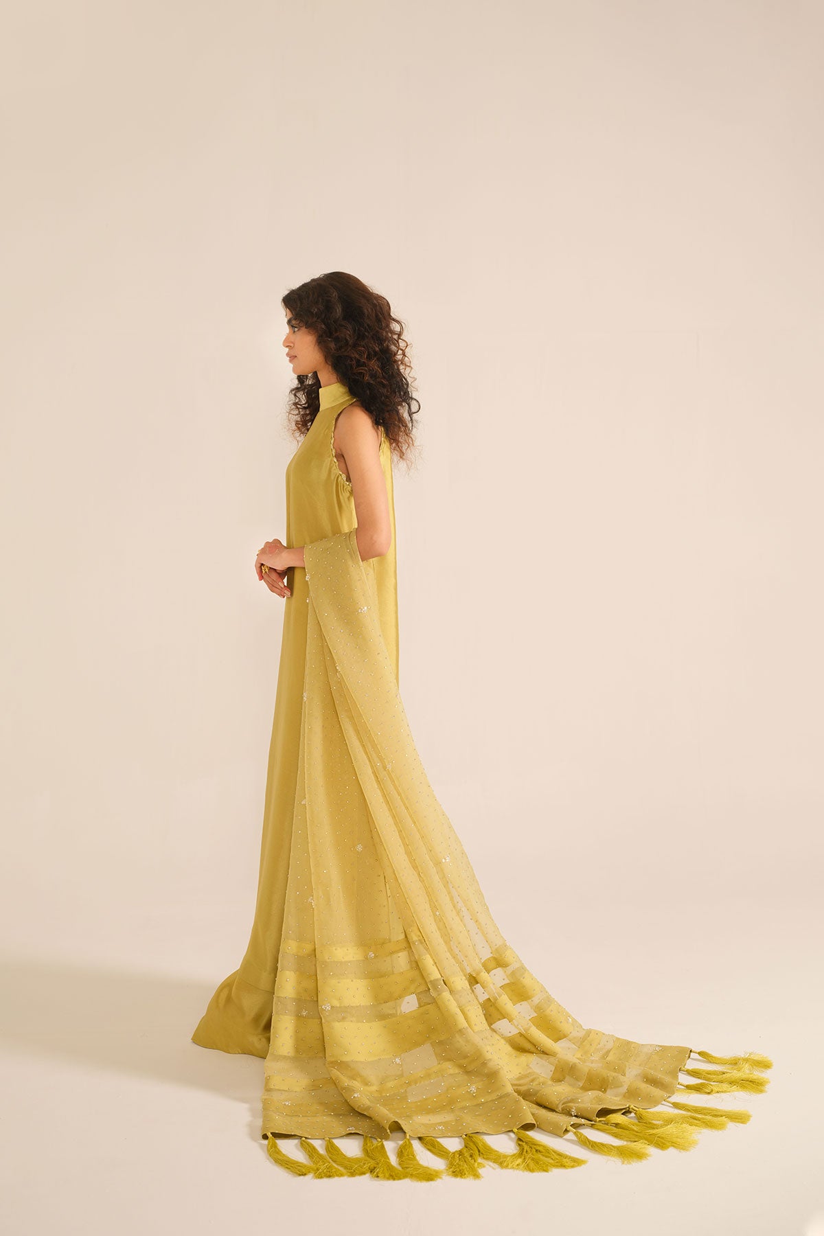 Model in a back closeup shot wearing mustard tissue silk shirt with a halter neckline paired with flared pants and silk organza dupatta