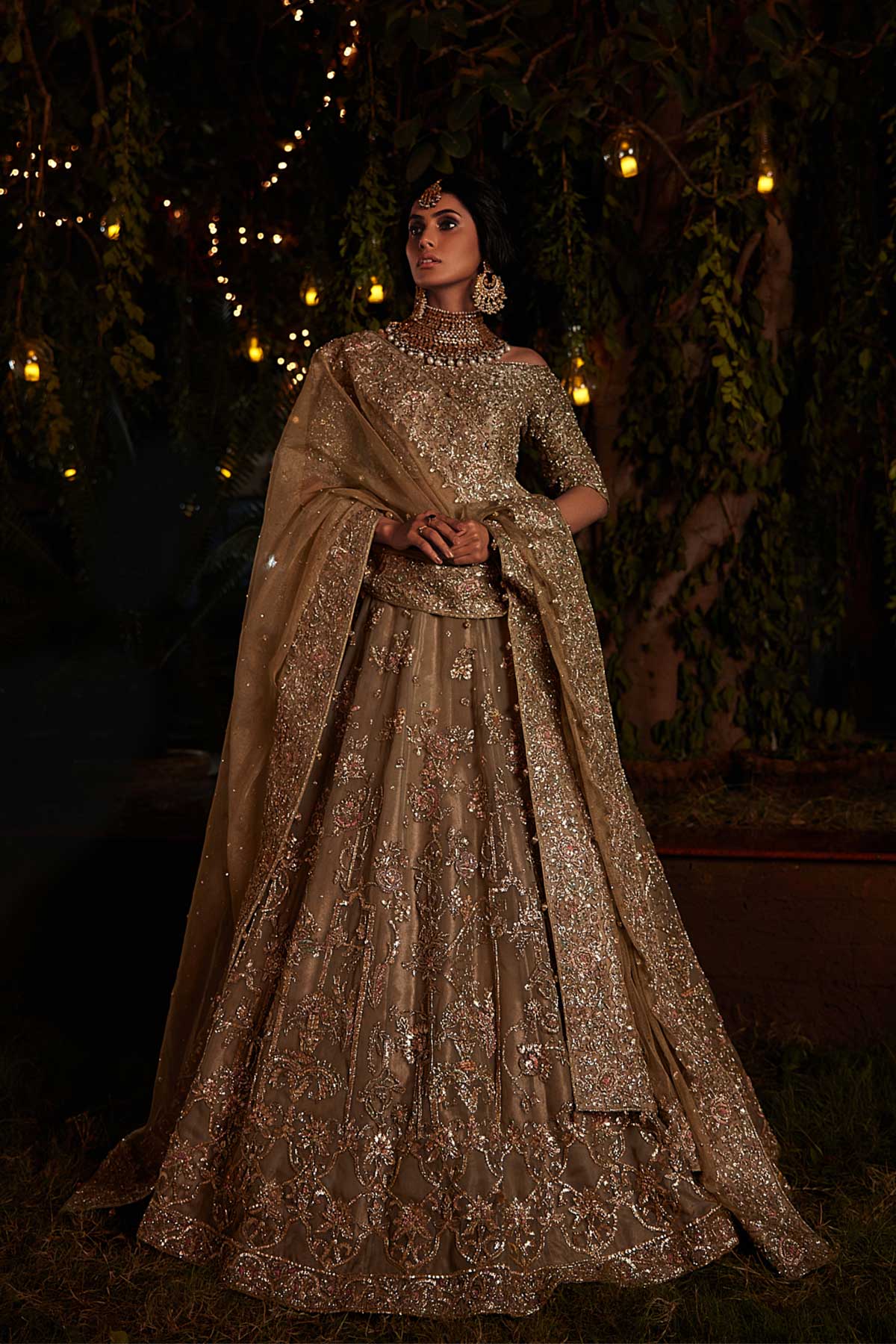 model in a front shot wearing a bridal olive green lehenga paired with off-shoulder choli and zari net dupatta