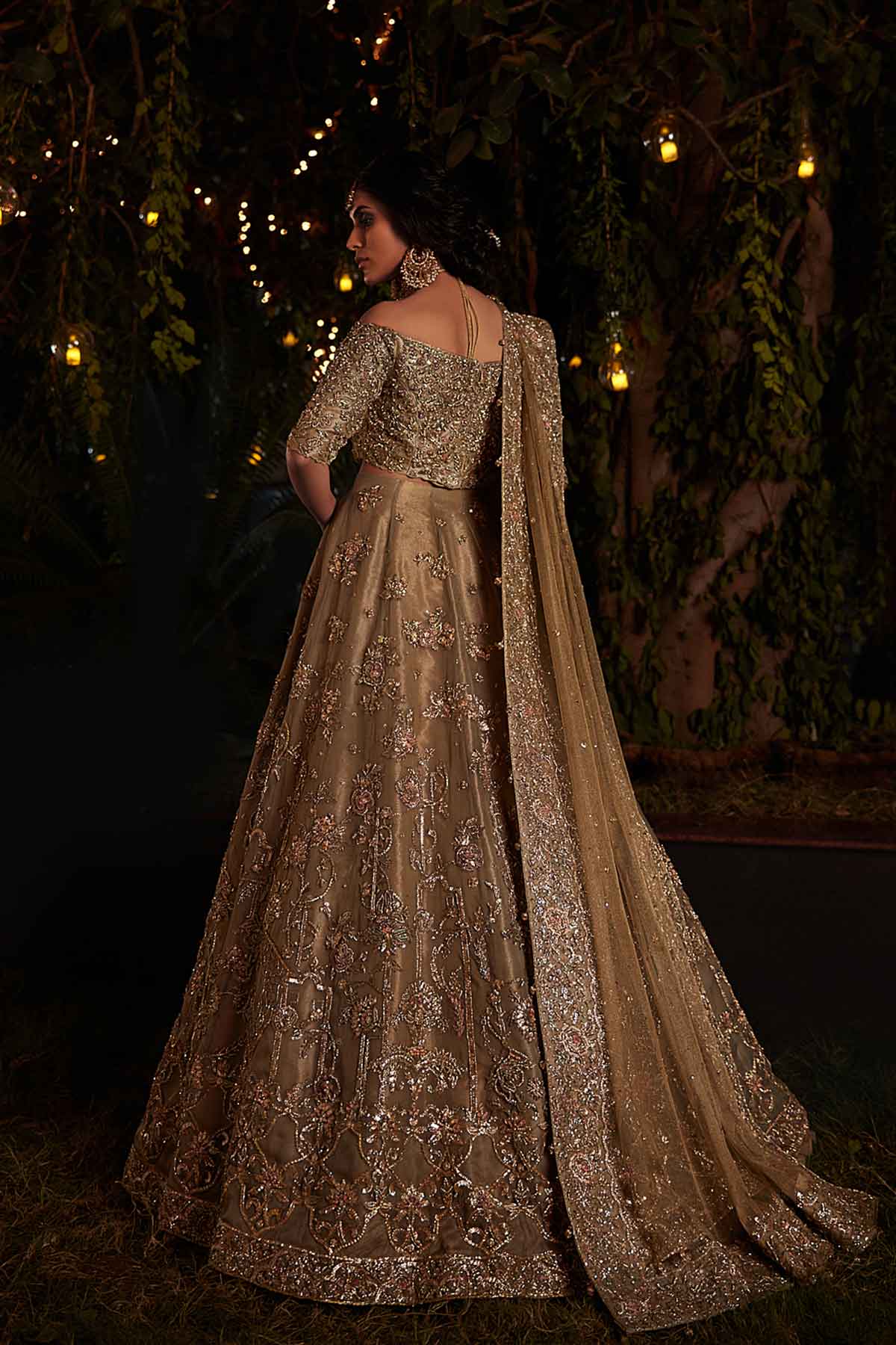 model in a back wearing a bridal olive green lehenga paired with off-shoulder choli and zari net dupatta