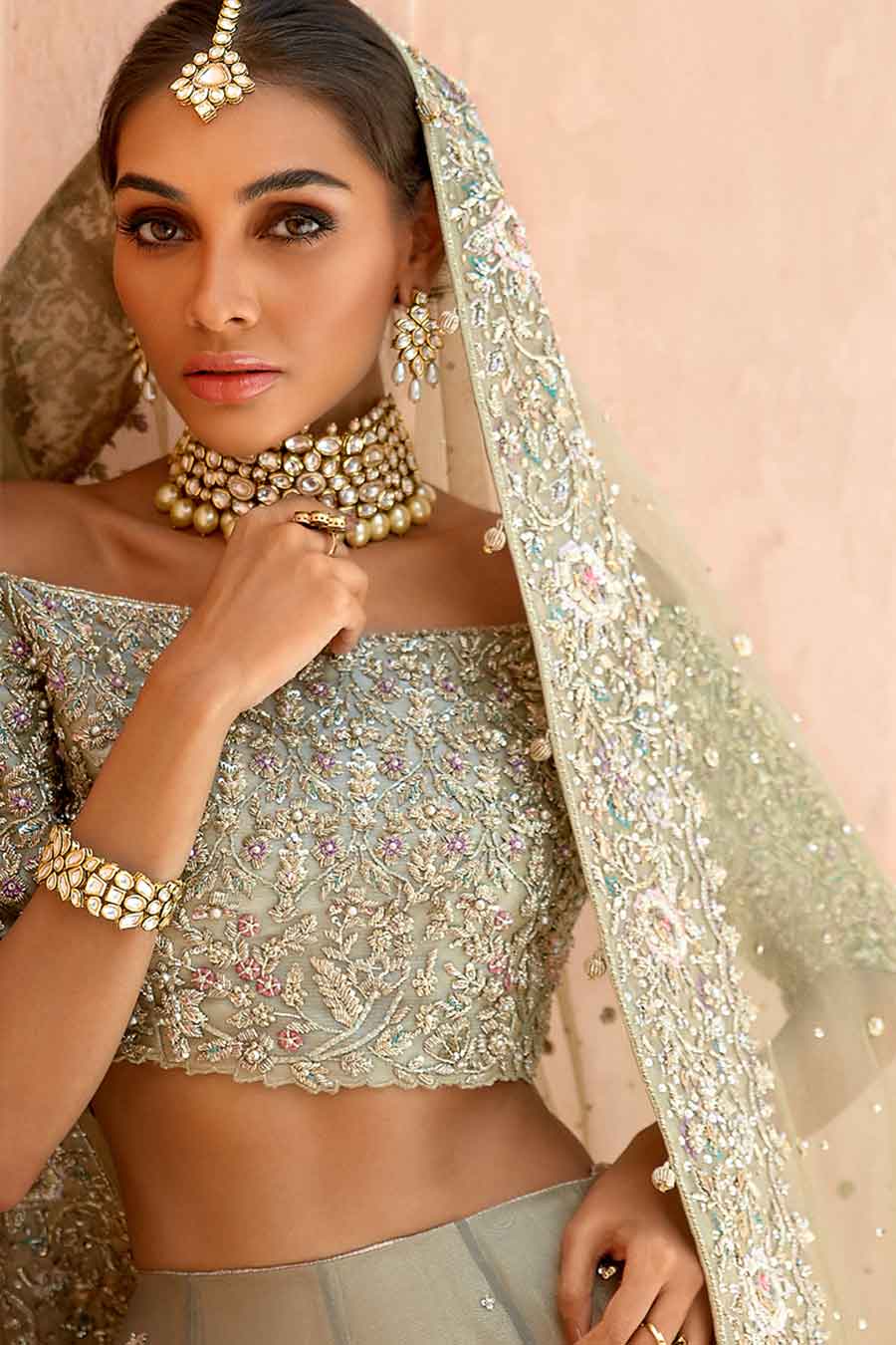 model in a front closeup shot wearing a bridal olive green lehenga paired with off-shoulder choli and zari net dupatta
