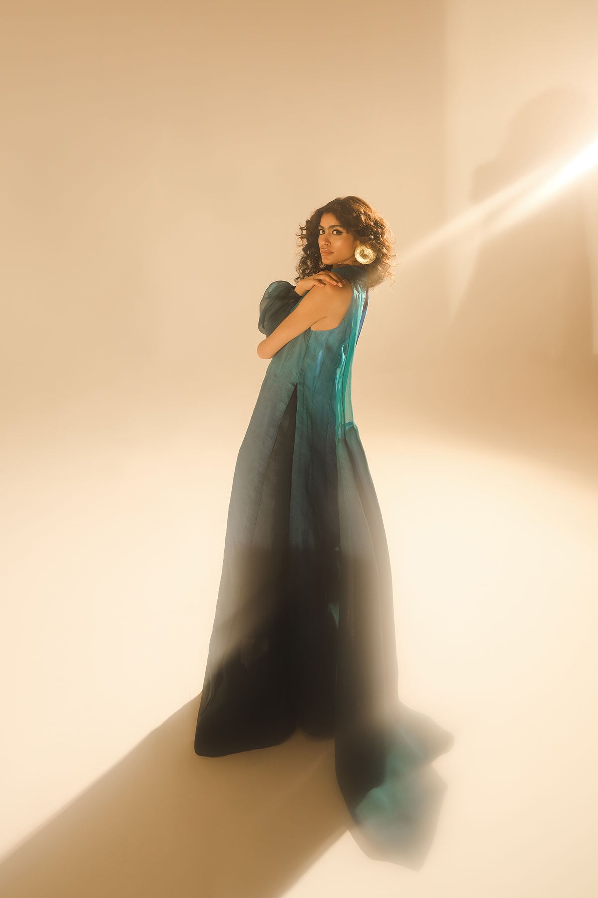 Model in a side shot wearing ombre silk organza shirt with silk organza drape attached paired with tissue silk pants