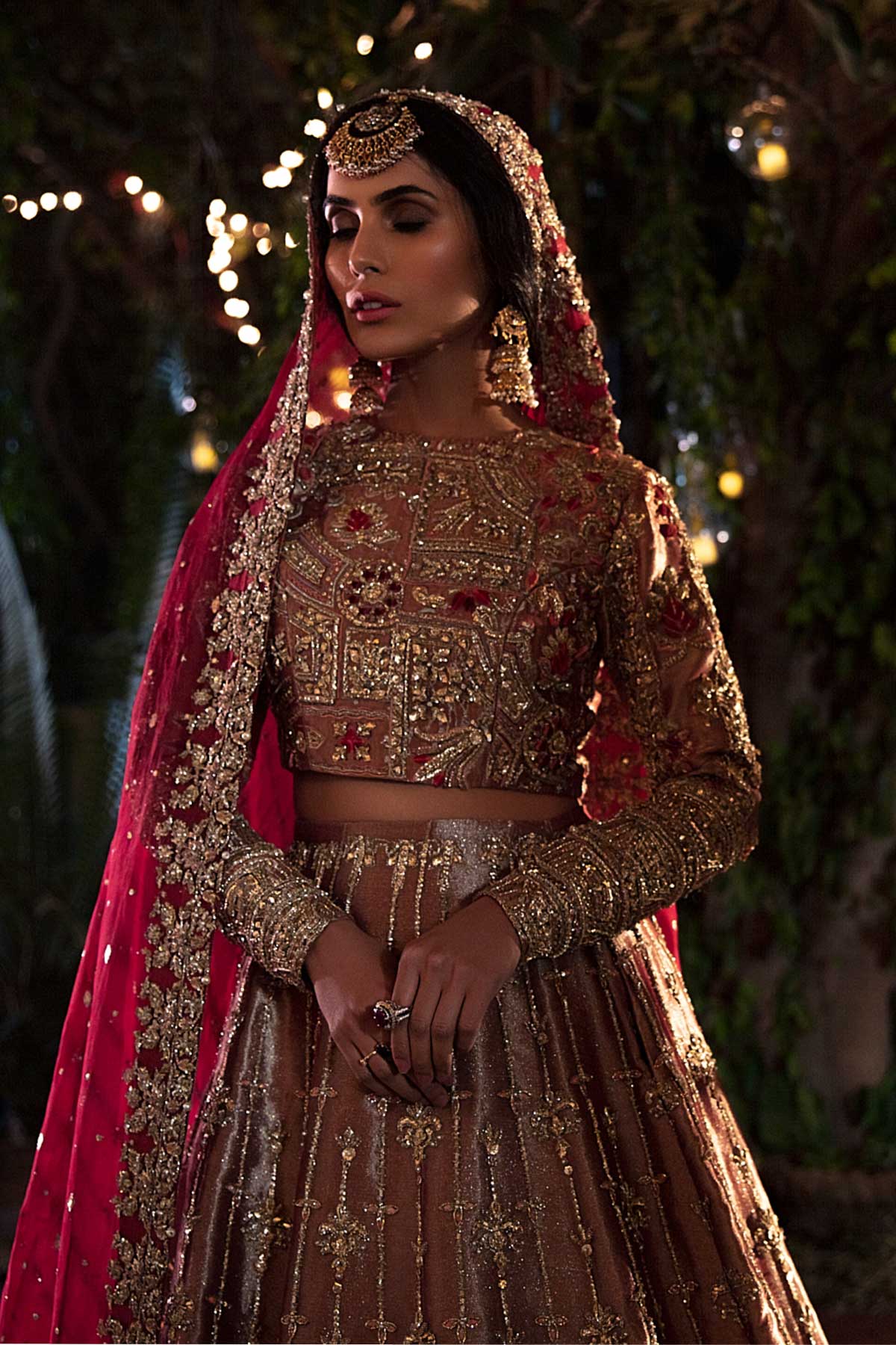 model in a closeup front shot wearing rust-colored bridal lehenga choli crafted in tissue fabric and silk organza dupatta