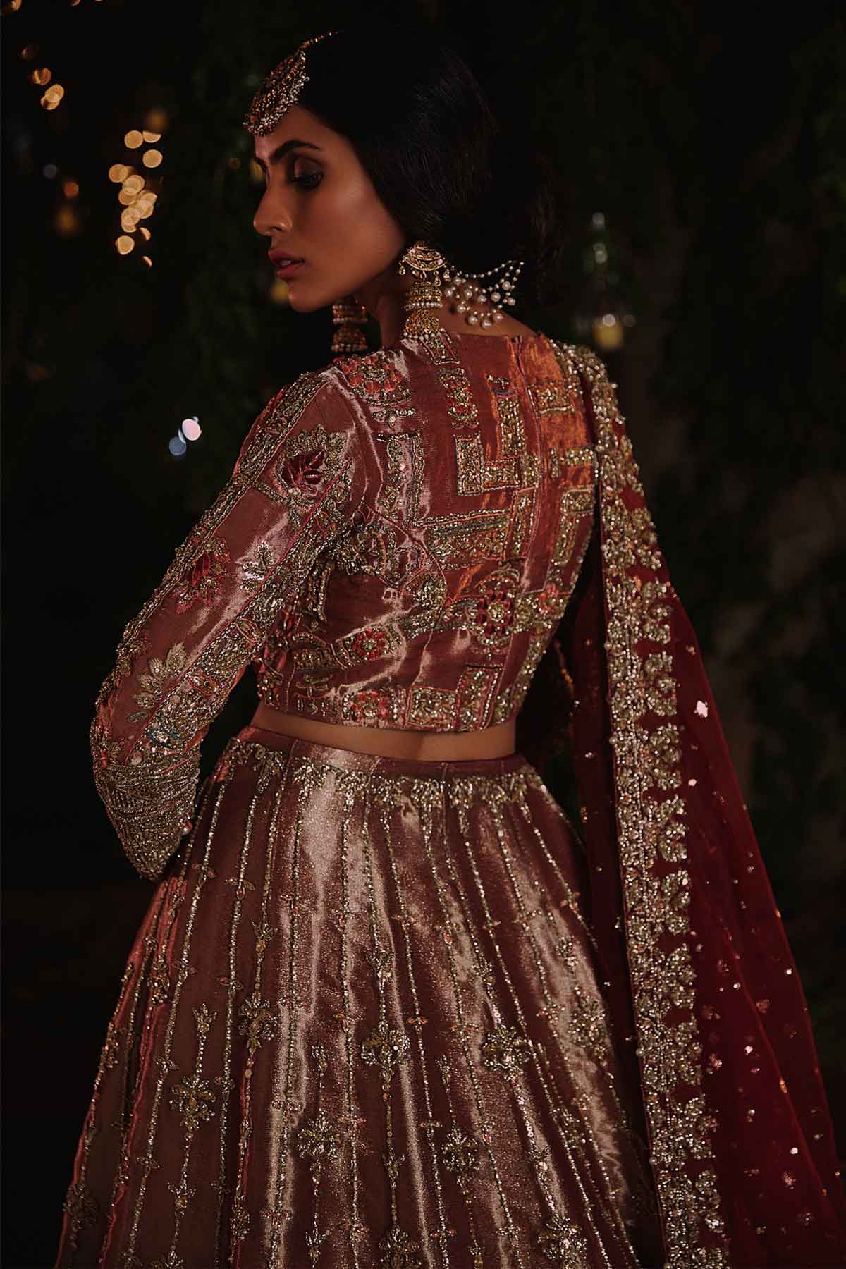 model in a back shot wearing rust-colored bridal lehenga choli crafted in tissue fabric and silk organza dupatta
