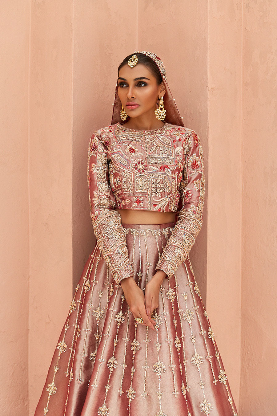 model in a front half shot wearing rust-colored bridal lehenga choli crafted in tissue fabric and silk organza dupatta