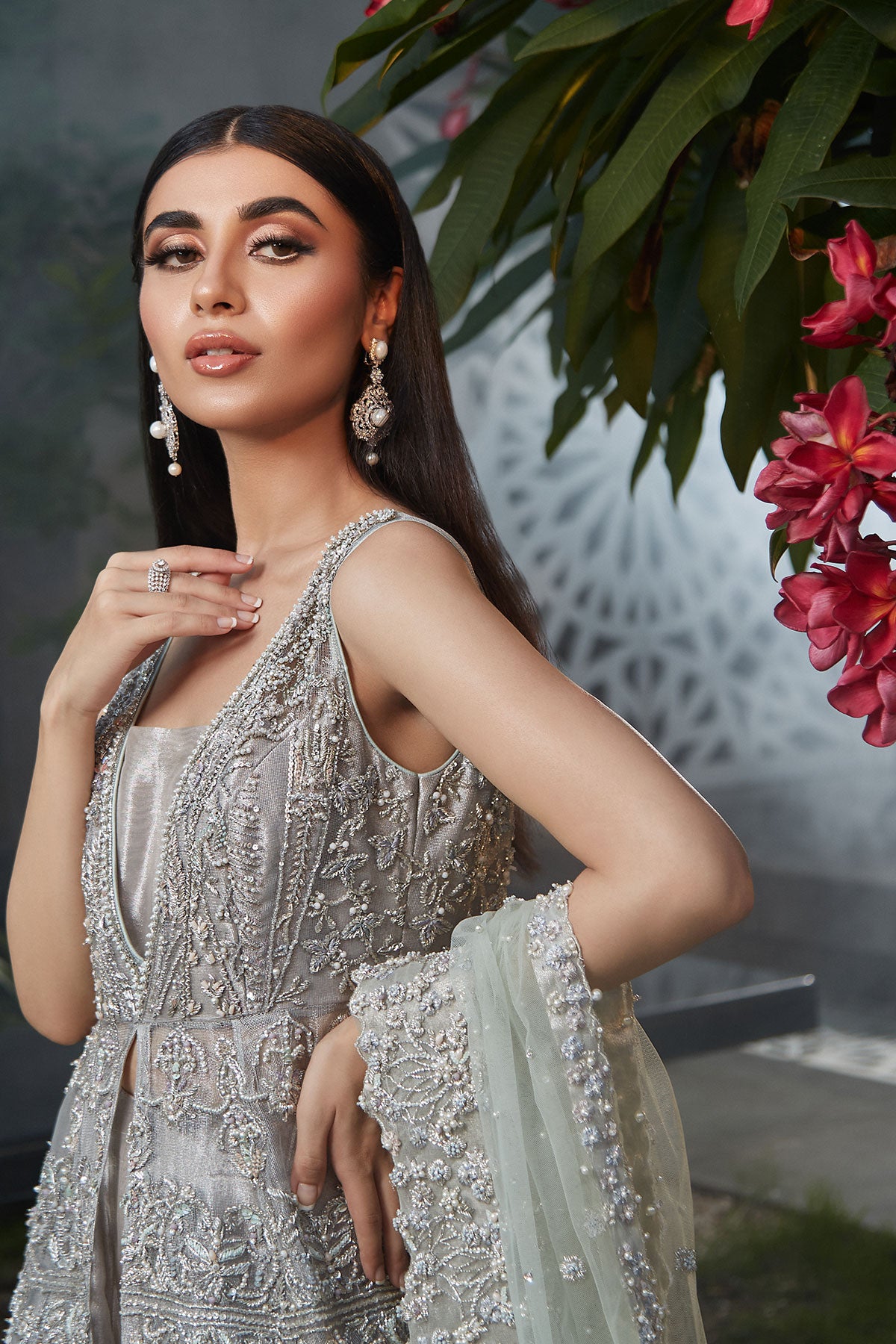 model in a closeup shot wearing silver bridal net front-open sleeveless gown paired with a tissue sharara and net dupatta